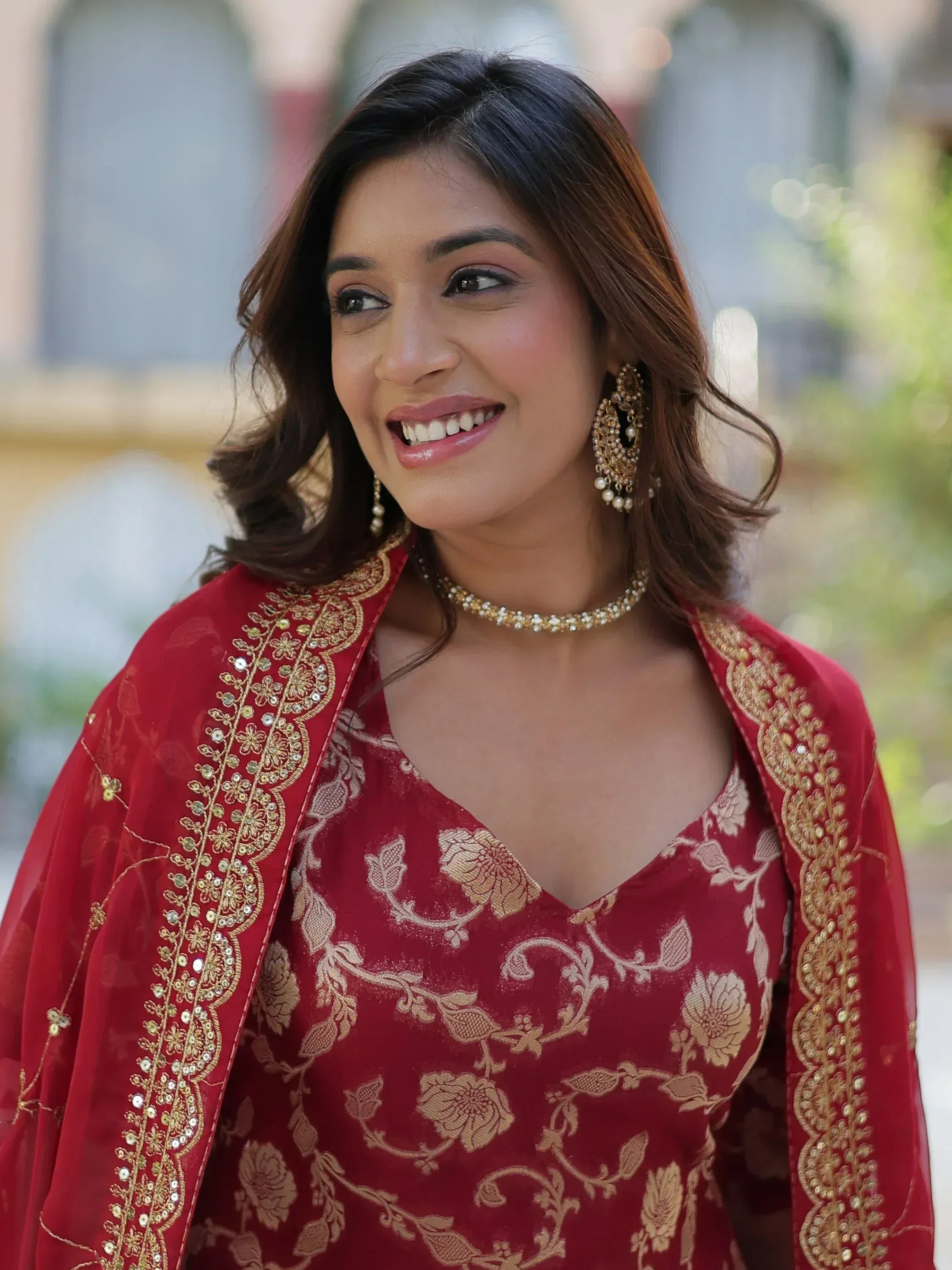 Red floral embroidered ethnic gown with gold detailing and matching jewelry