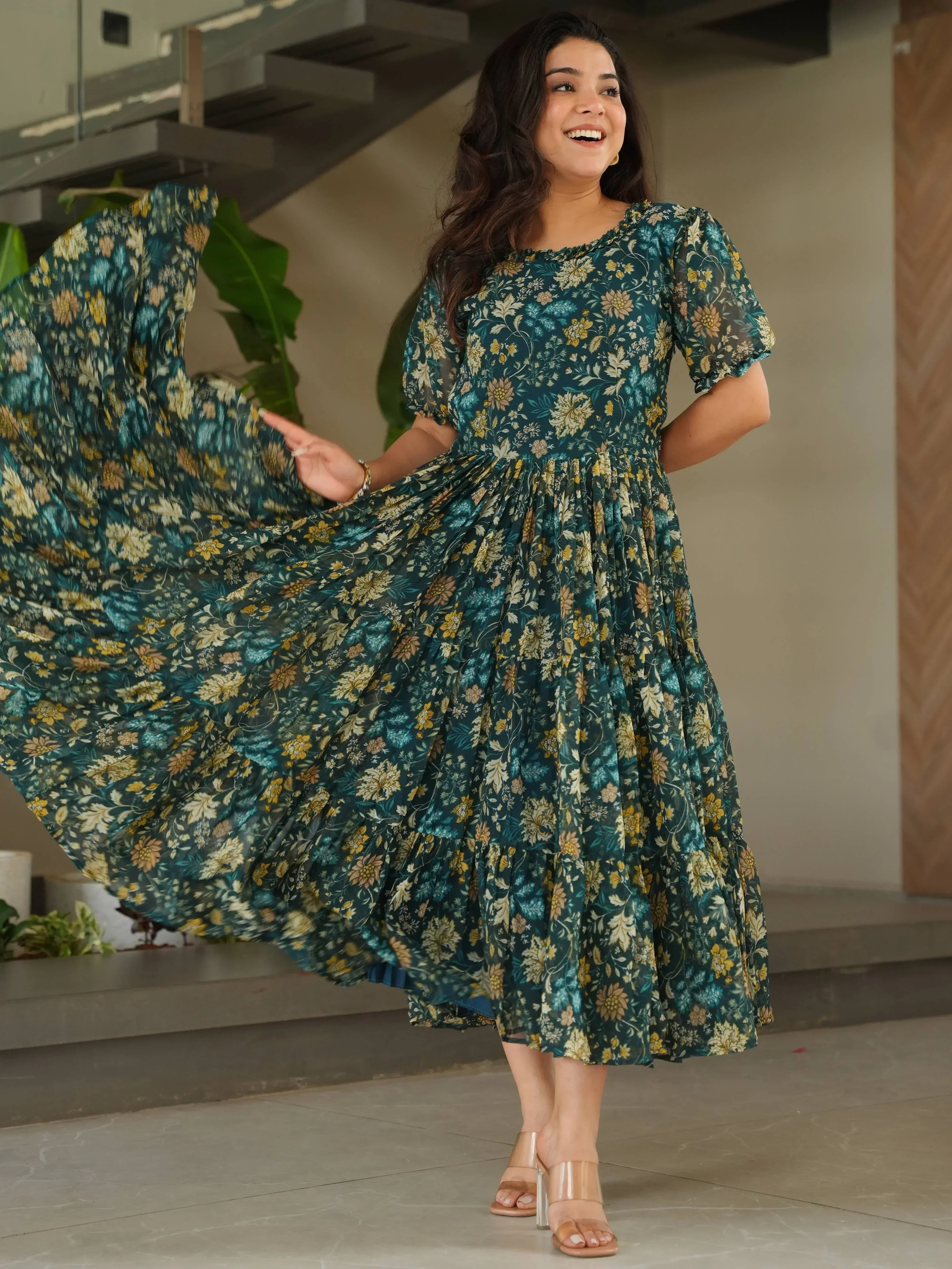 Woman in flowing green floral ethnic gown with puff sleeves, twirling indoors