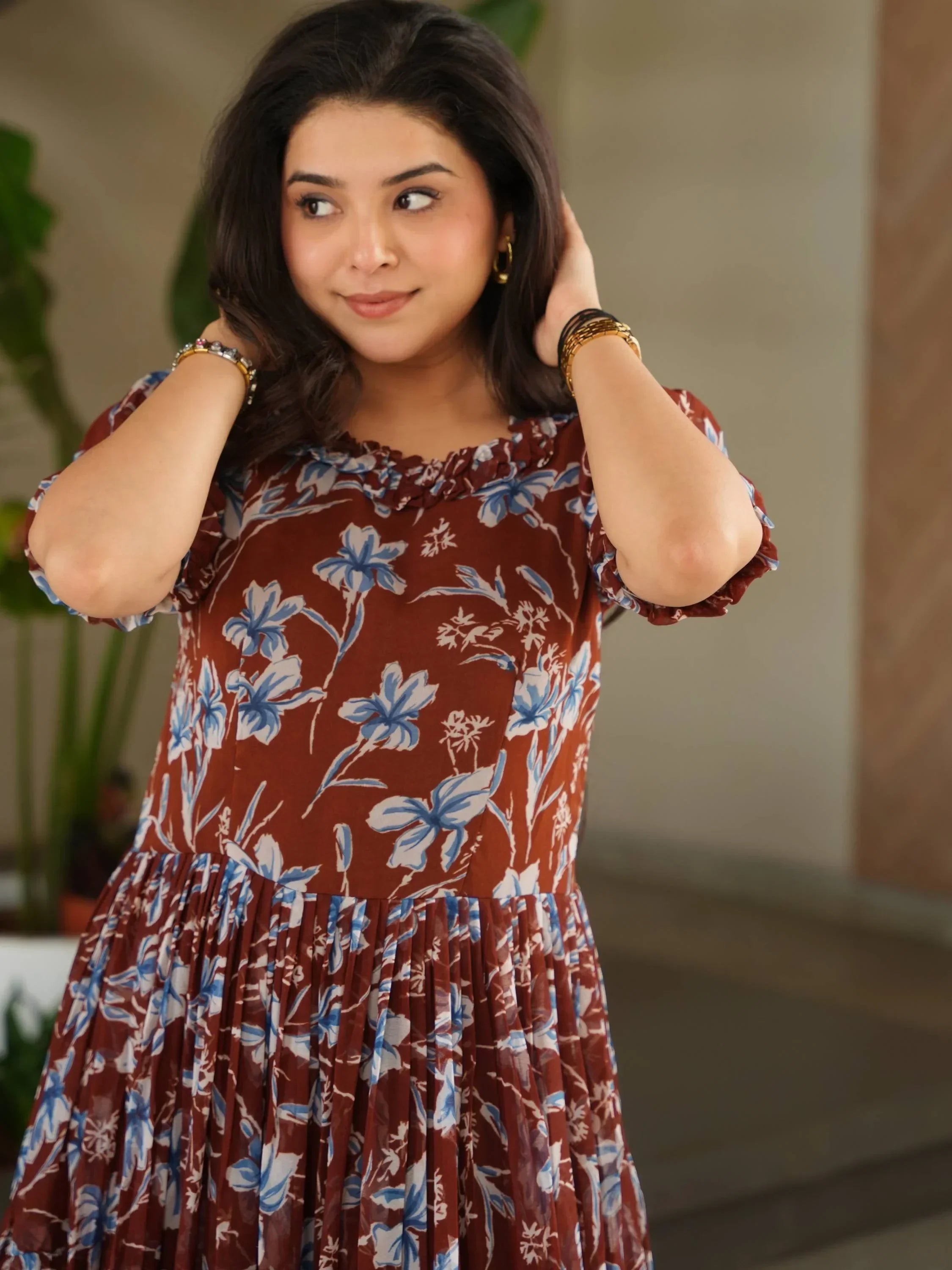 Woman in maroon floral ethnic dress with blue and white flower pattern, indoors