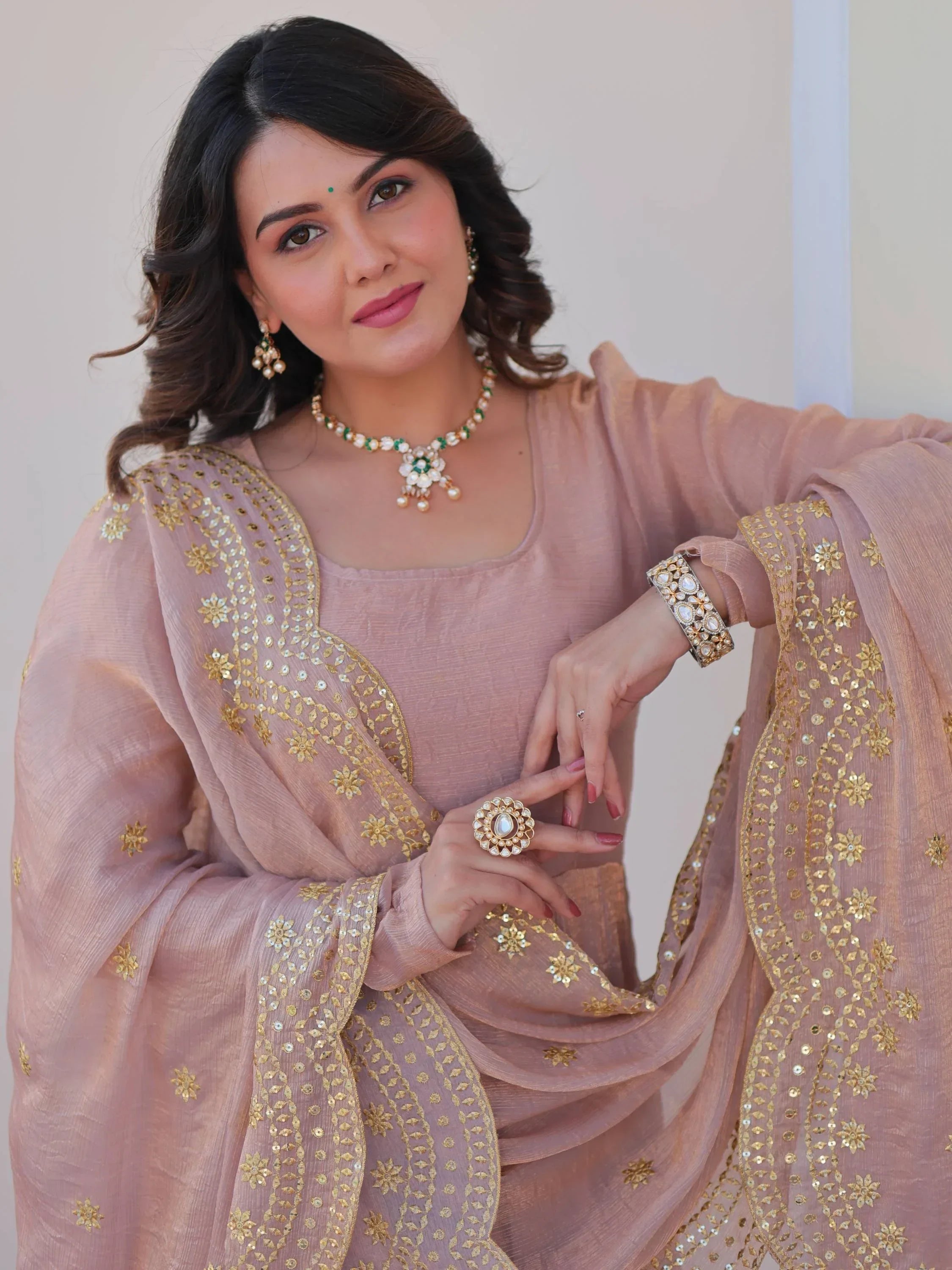 Woman in peach embroidered ethnic saree with gold details and traditional jewelry
