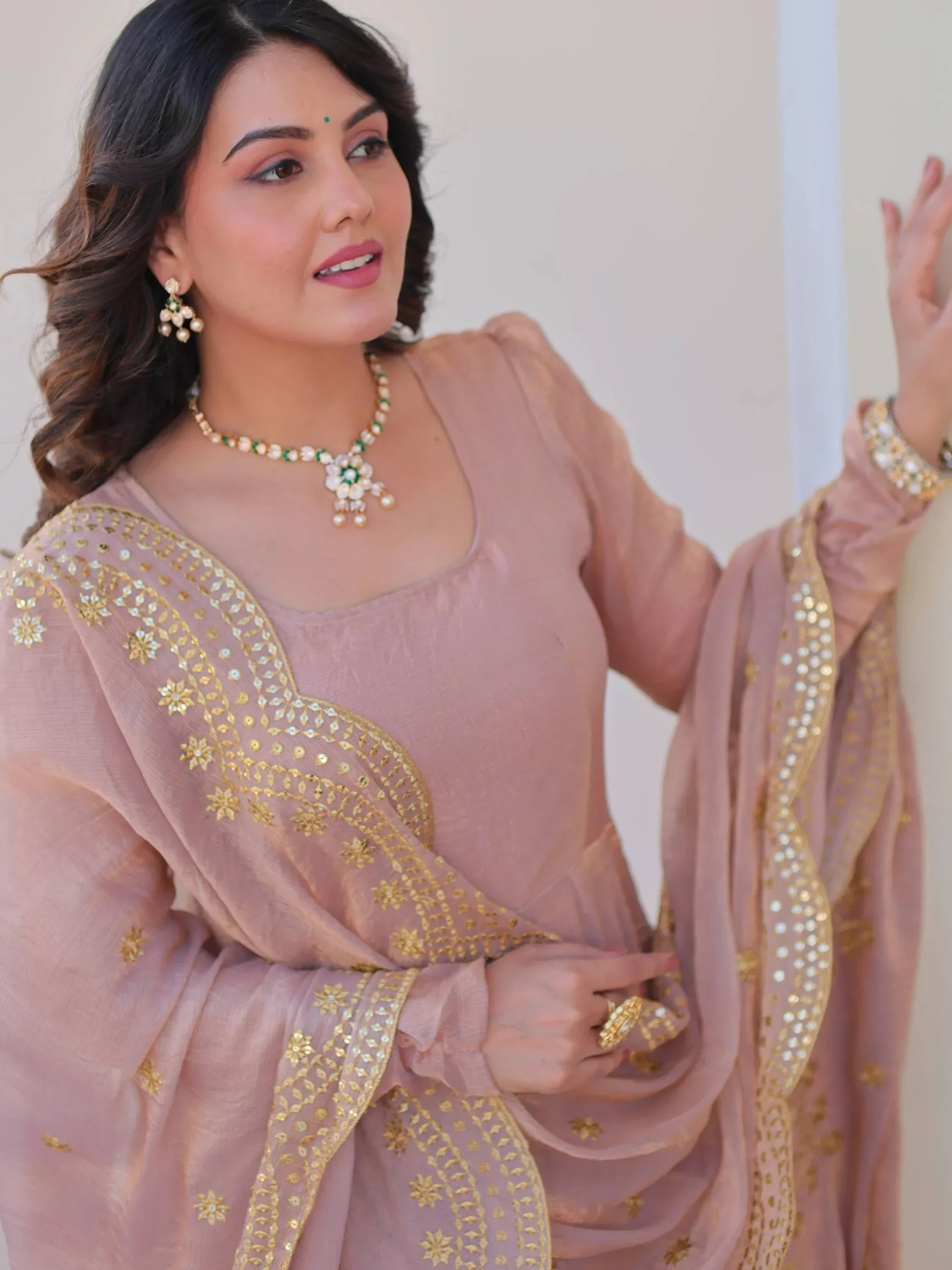 Woman in light brown ethnic saree with golden embroidery and matching jewelry
