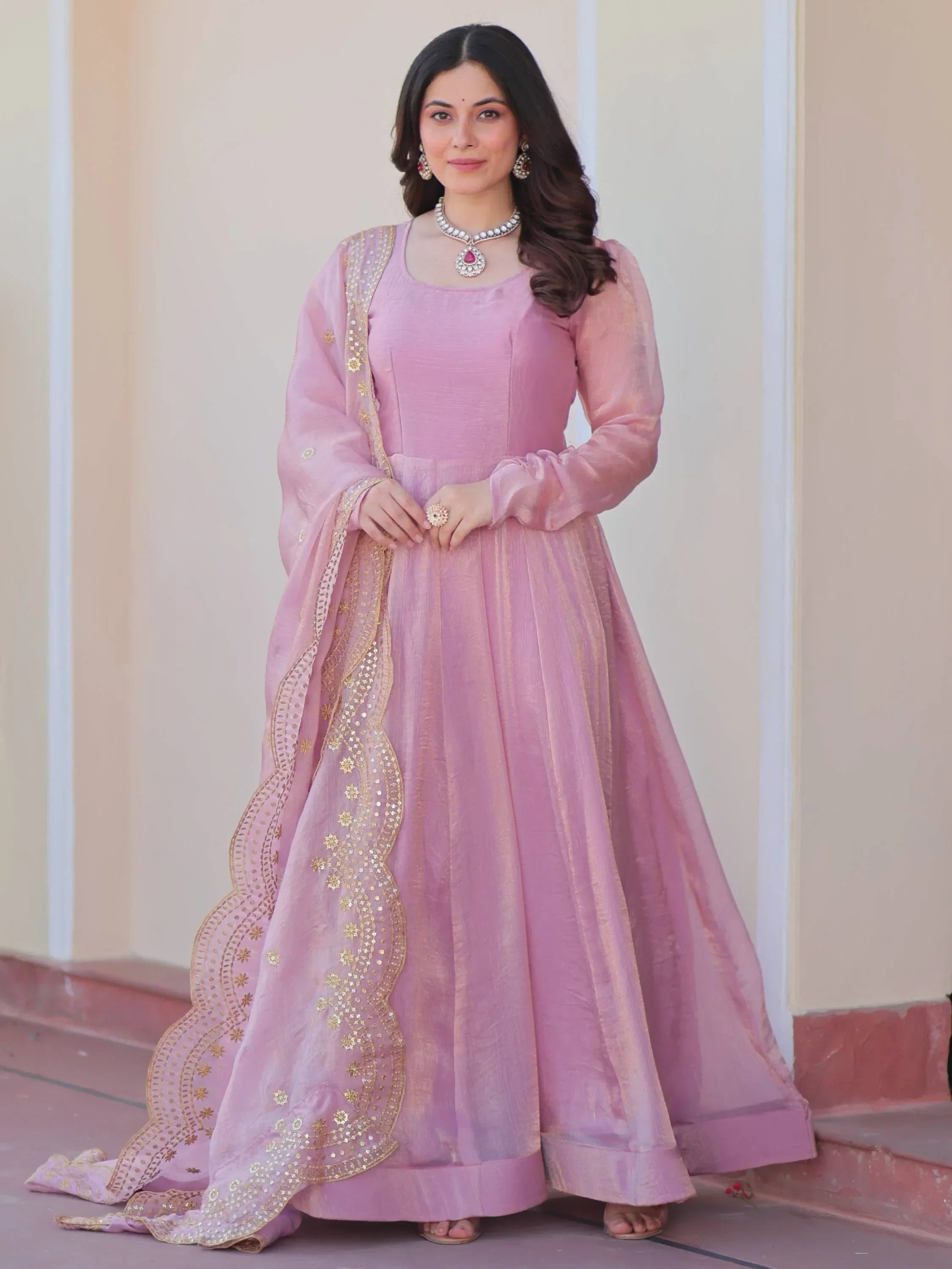Woman in light pink ethnic gown with sheer dupatta featuring gold embroidery