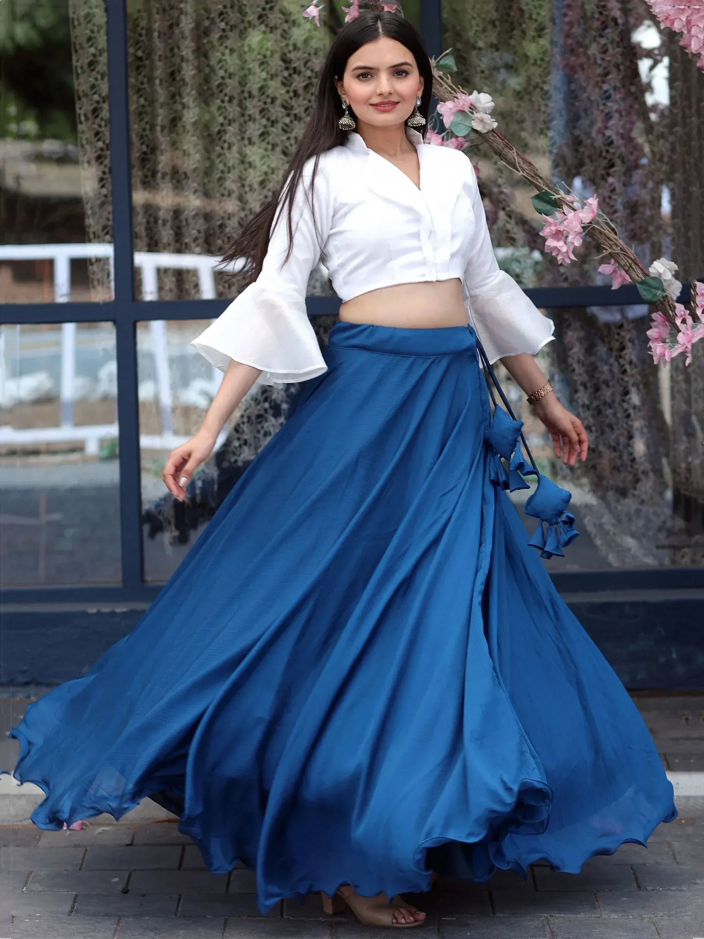 Woman in white crop top with bell sleeves and blue flared skirt, ethnic wear outfit