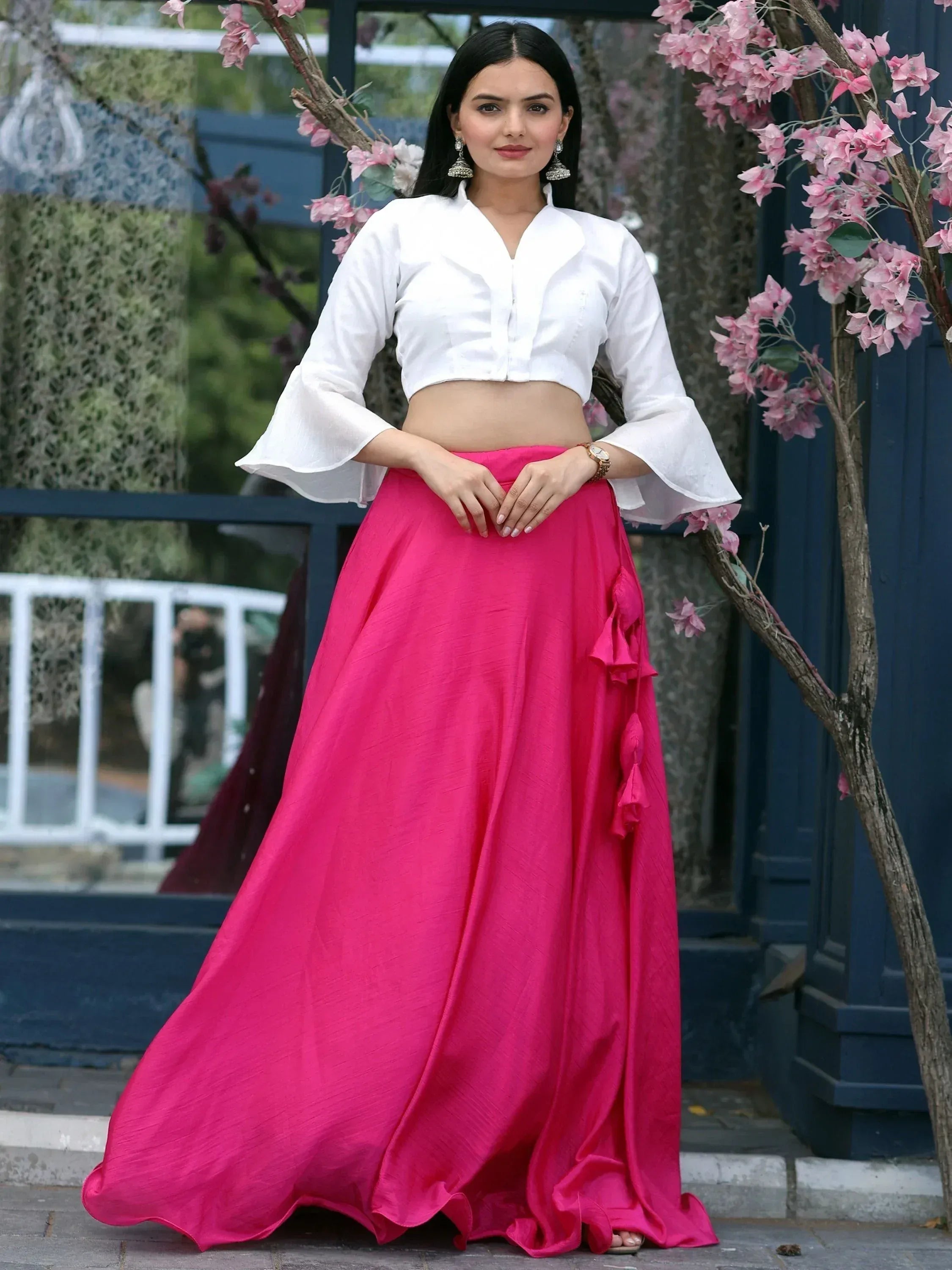 Woman in white crop top and pink ethnic skirt with floral backdrop