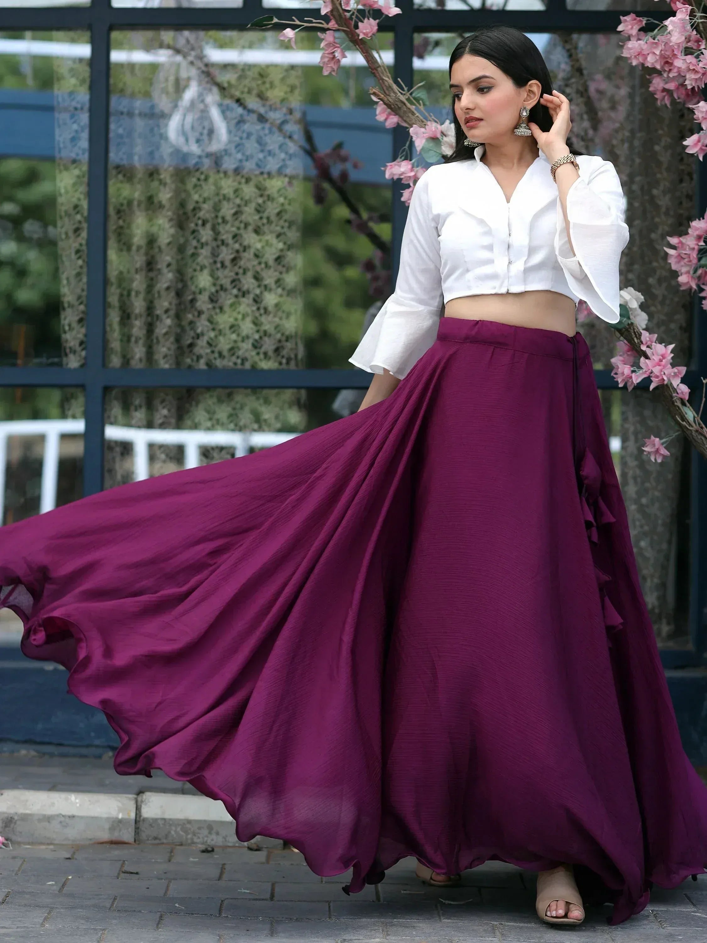 Woman in white crop top and flowing purple skirt, Indian ethnic wear with flared sleeves and ruffles
