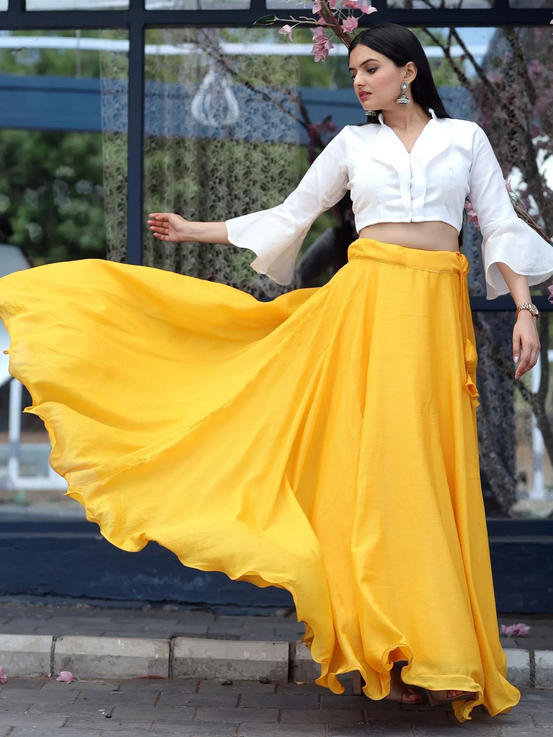 Woman in white crop top and flowing yellow skirt, ethnic wear outfit for festive occasions