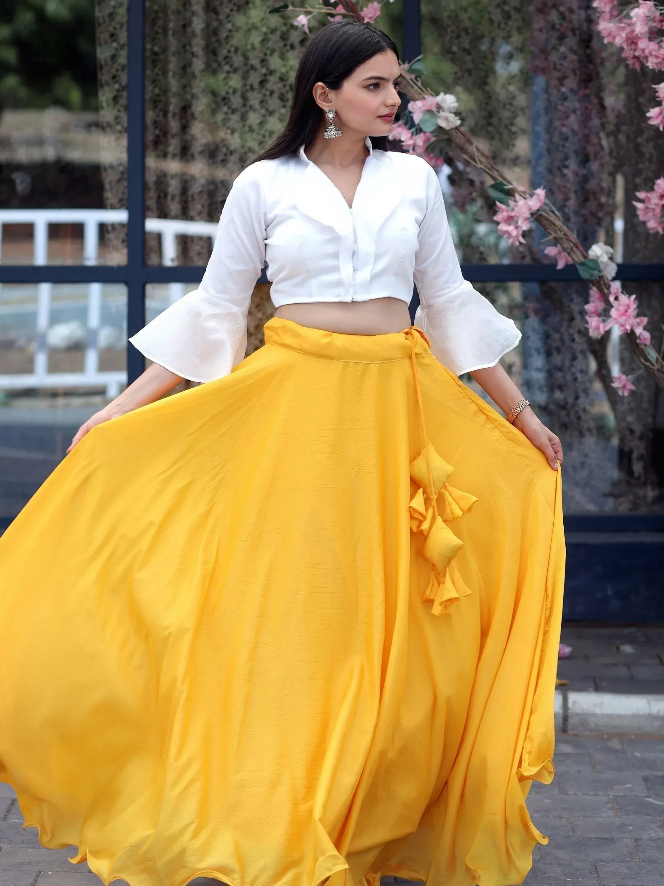 Yellow ethnic skirt with white crop top, ruffle details, and floral backdrop
