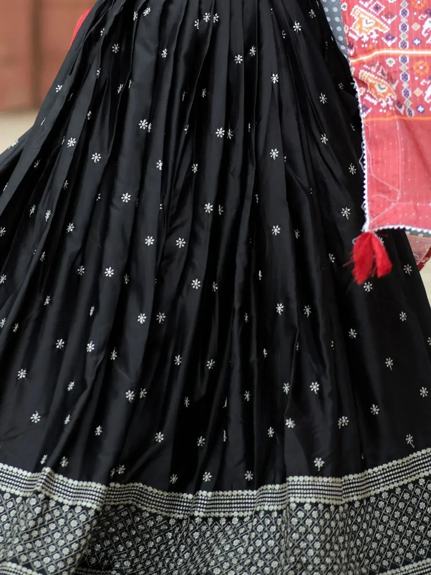Black ethnic skirt with white floral embroidery and border, paired with red patterned dupatta