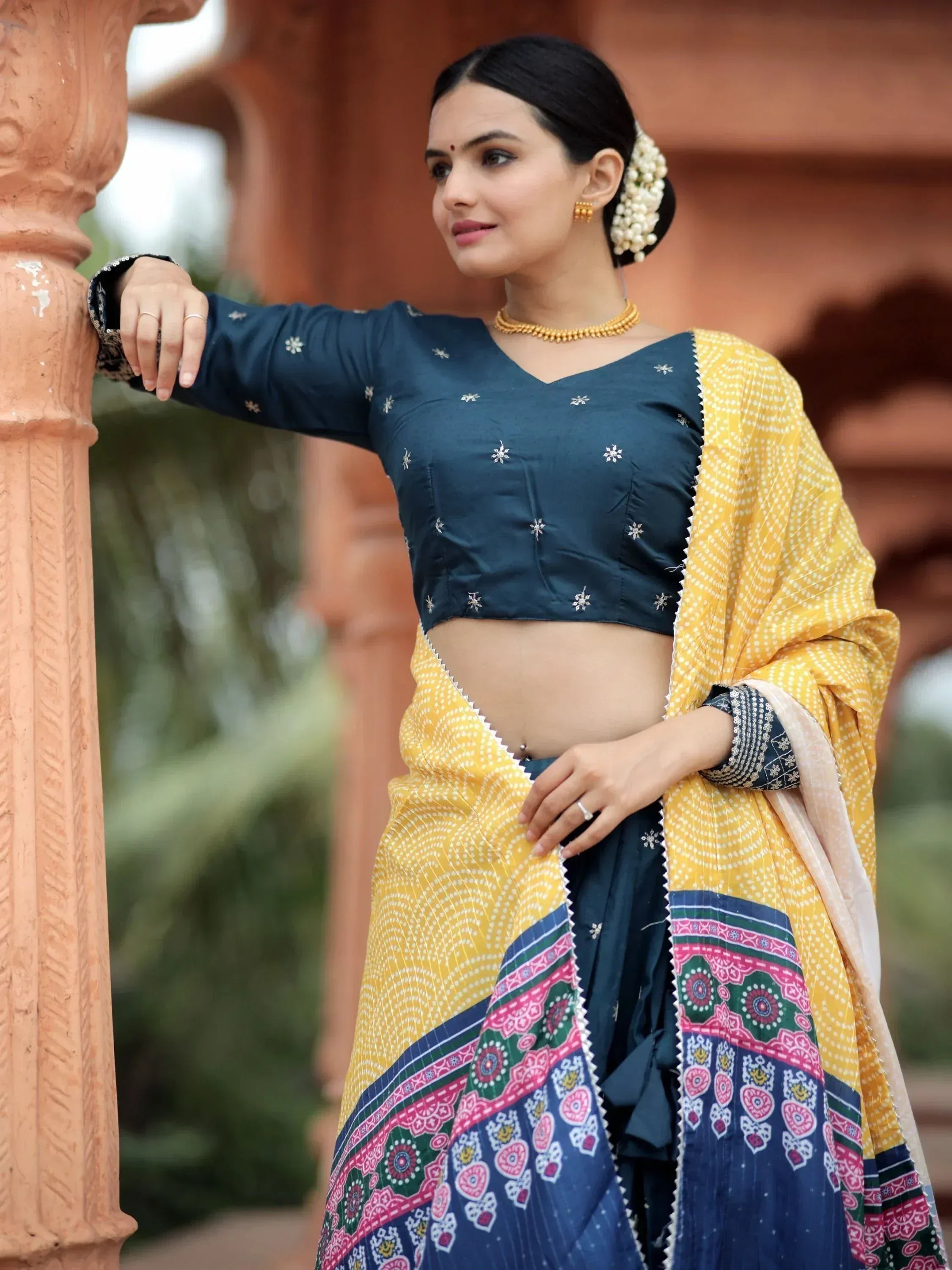 Woman in navy blue embroidered crop top with yellow printed saree, traditional Indian ethnic wear