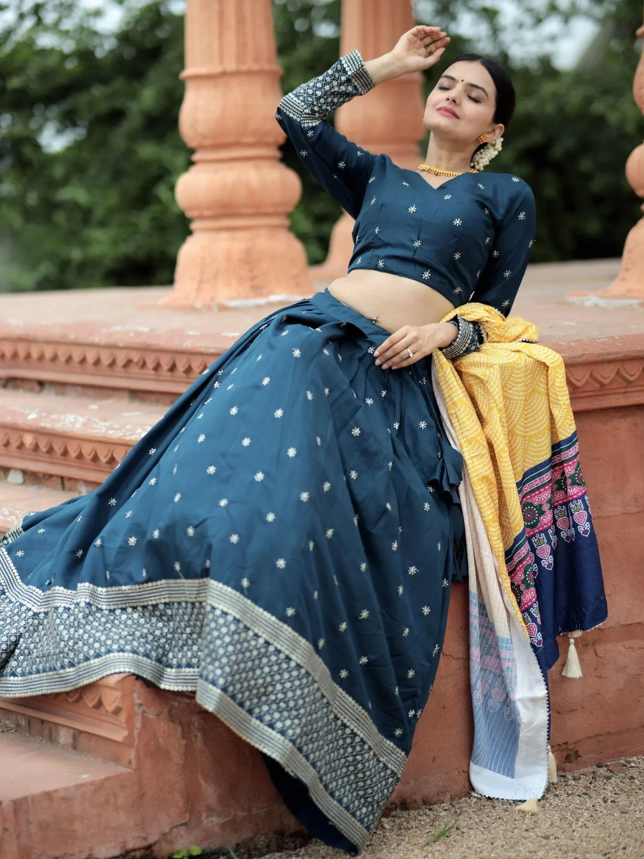 Woman in navy blue embroidered lehenga choli with yellow dupatta, traditional Indian ethnic wear