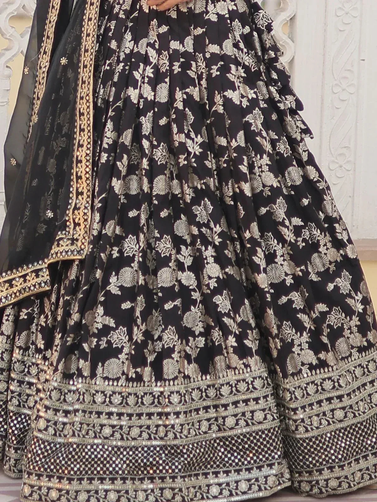 Black floral embroidered lehenga choli with gold detailing and ruffled hem, perfect for Indian ethnic wear.