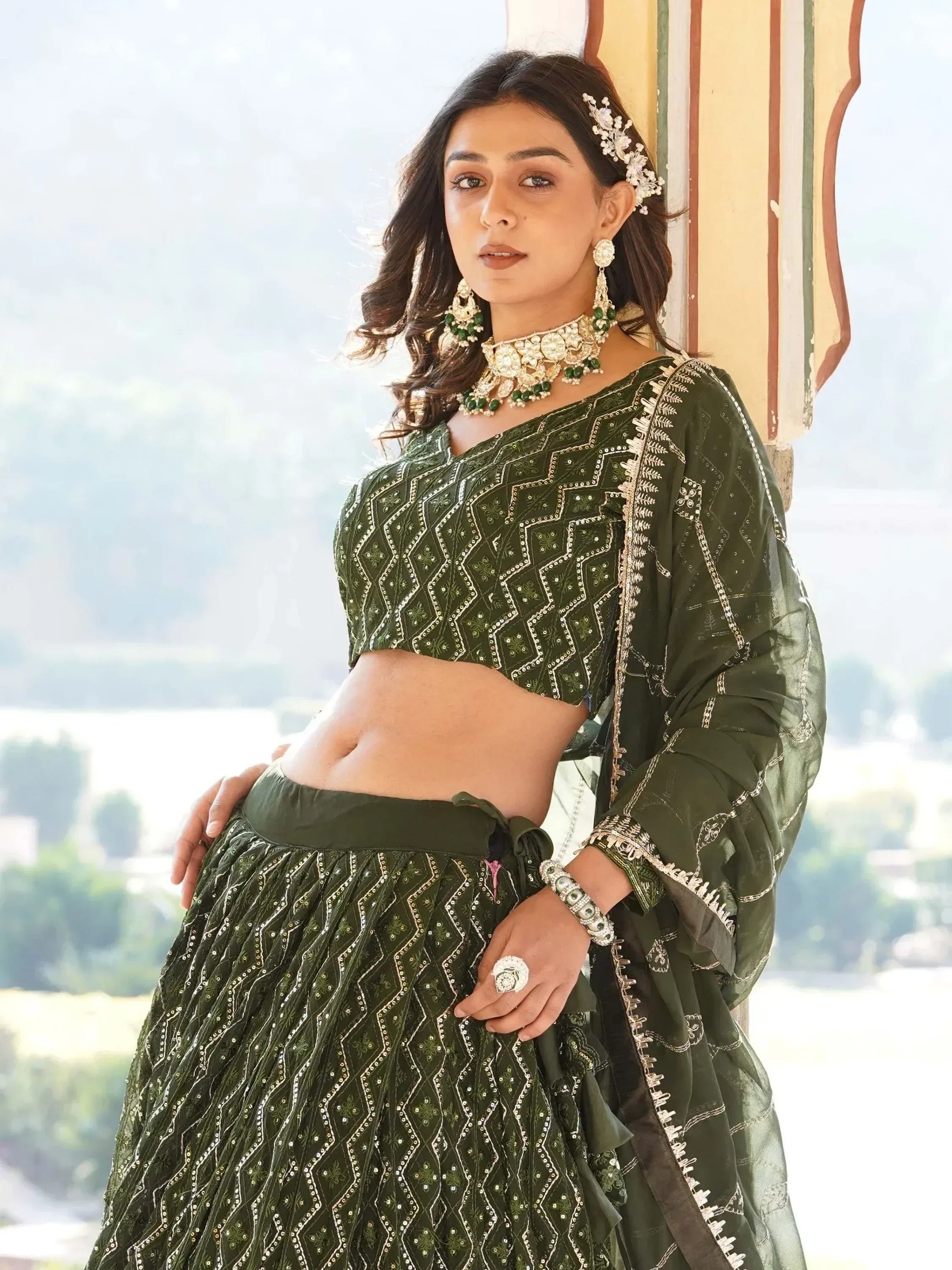 Woman in olive green embroidered lehenga choli with matching jewelry, perfect for Indian ethnic occasions.