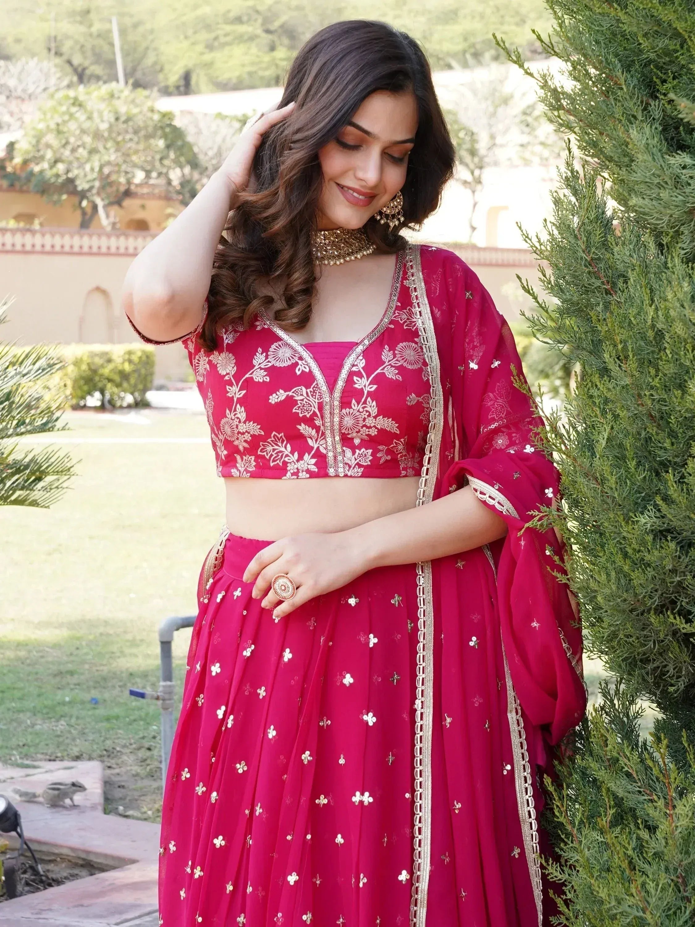 Woman in vibrant pink embroidered lehenga choli with gold detailing, perfect for Indian ethnic occasions