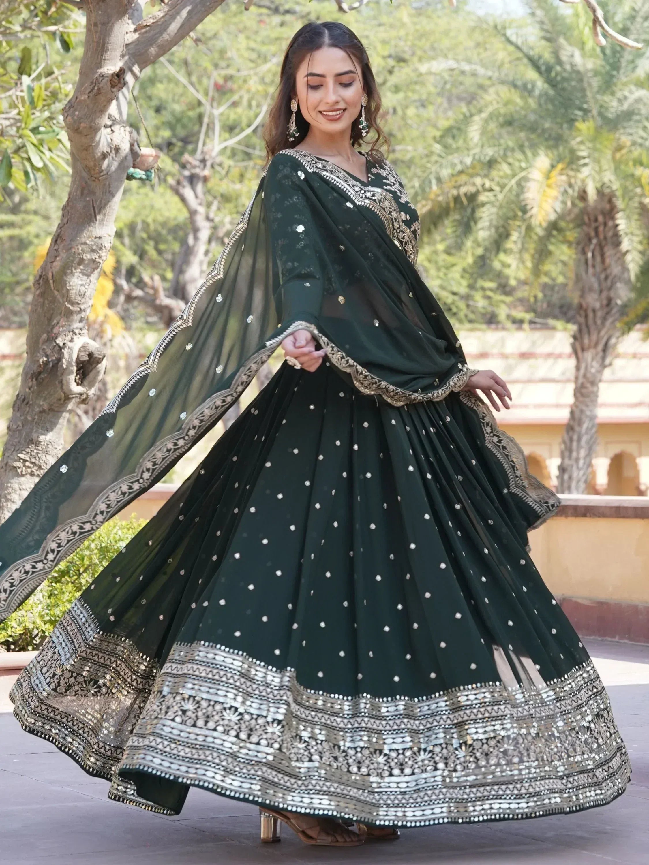 Elegant dark green ethnic lehenga choli with gold embroidery and mirror work, perfect for Indian weddings or festivals.