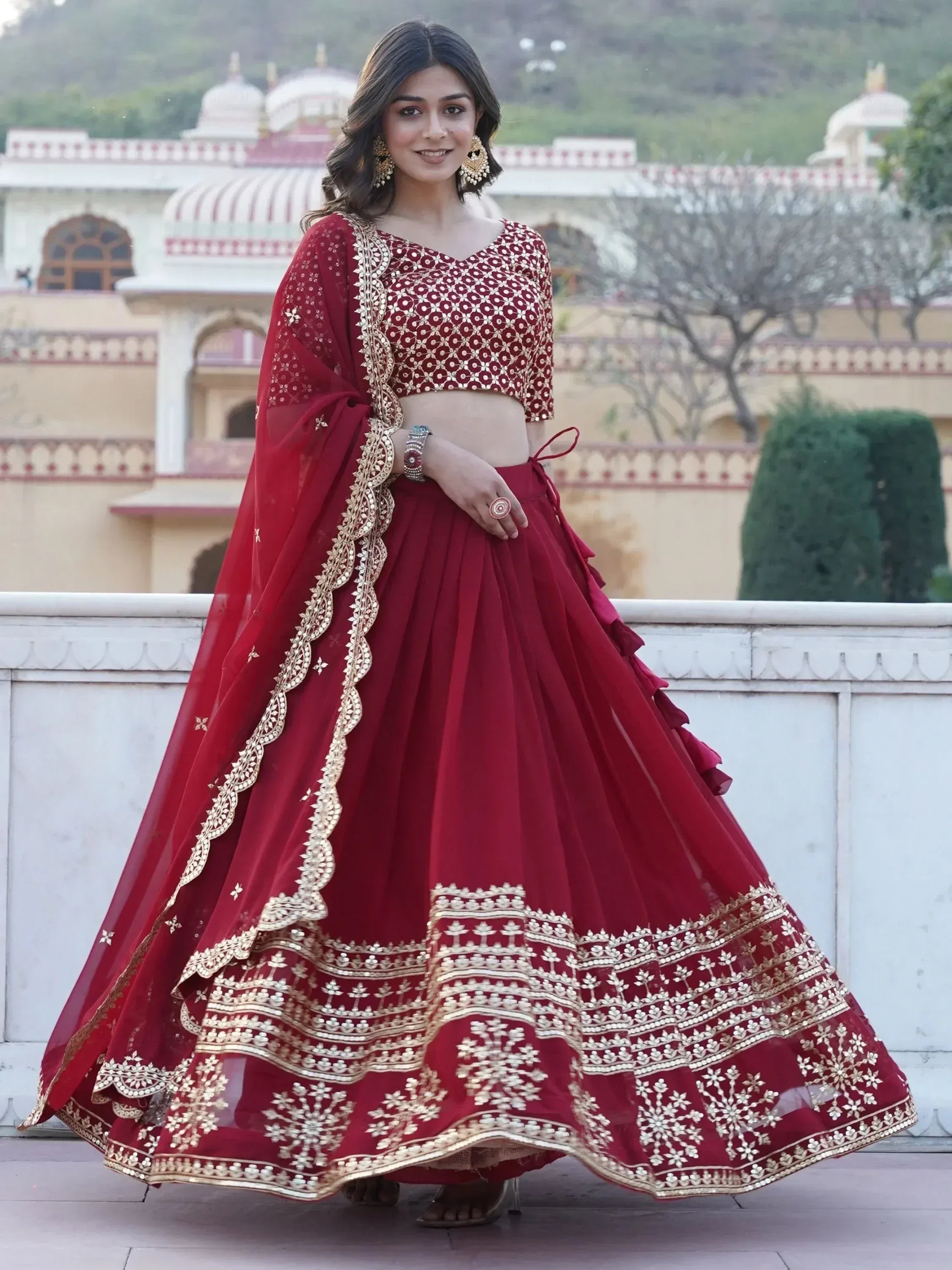 Woman in maroon designer lehenga choli with gold embroidery, perfect for Indian ethnic wear occasions