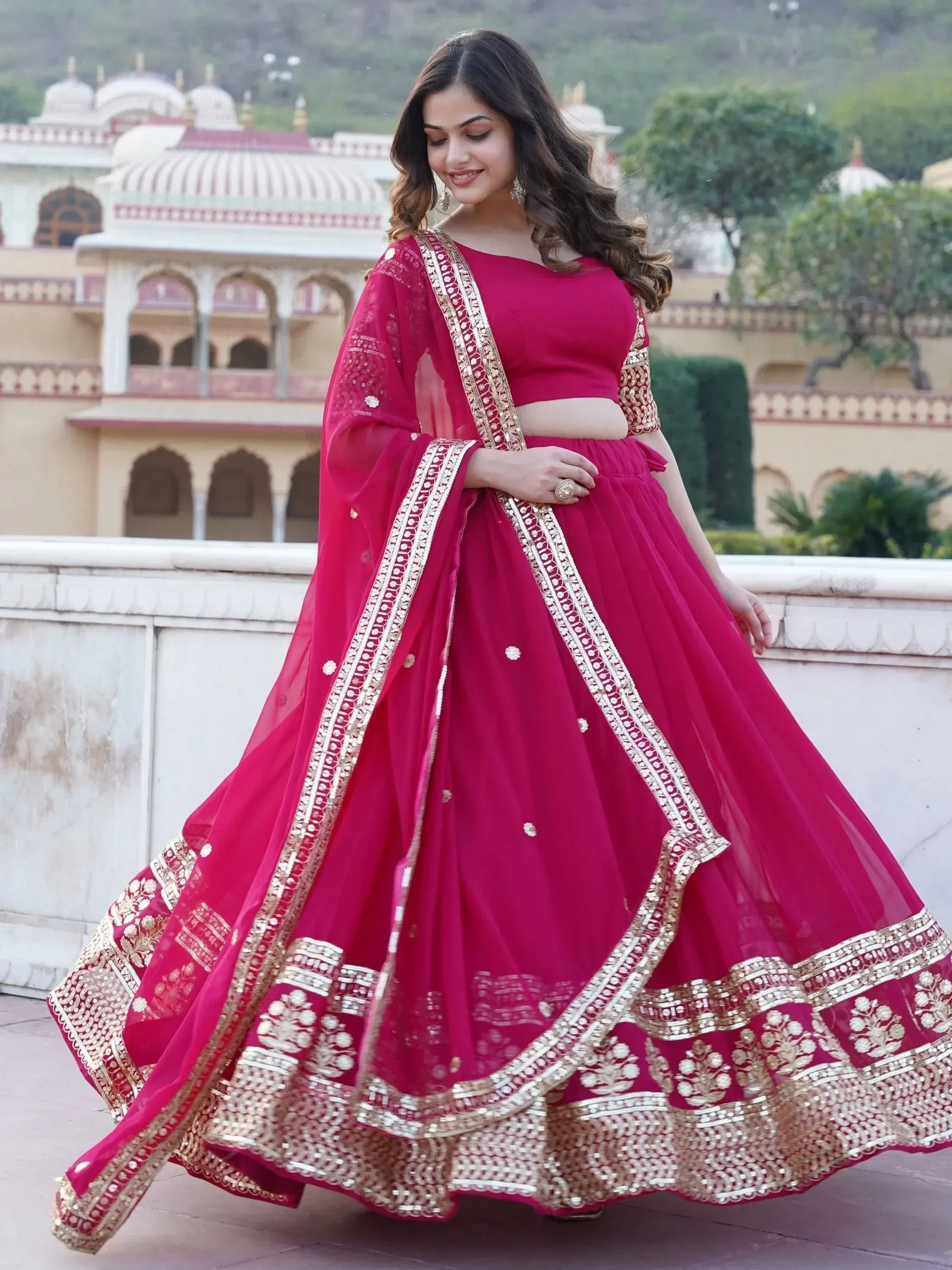 Woman in elegant magenta lehenga choli with gold embroidery, perfect for Indian ethnic wear occasions.