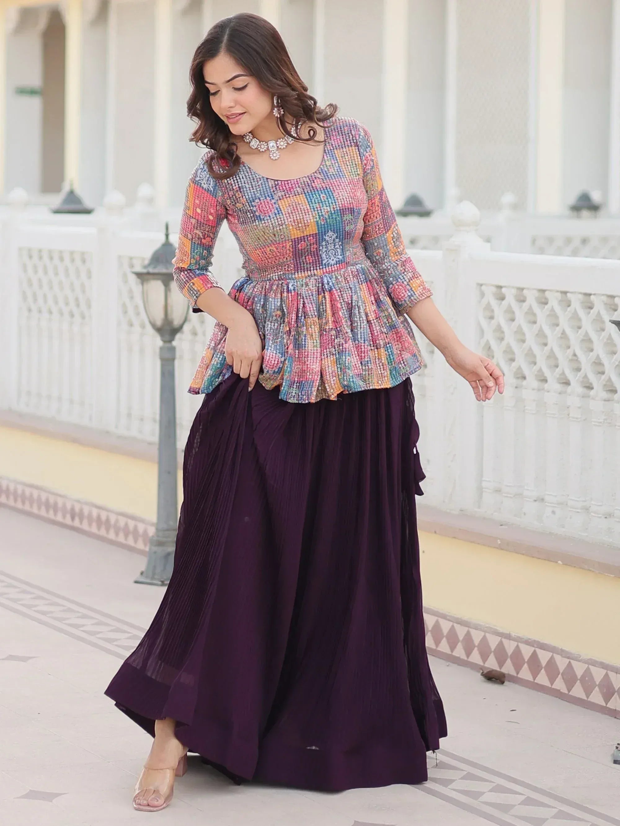 Woman in colorful patchwork peplum top with purple pleated skirt, ethnic Indian wear