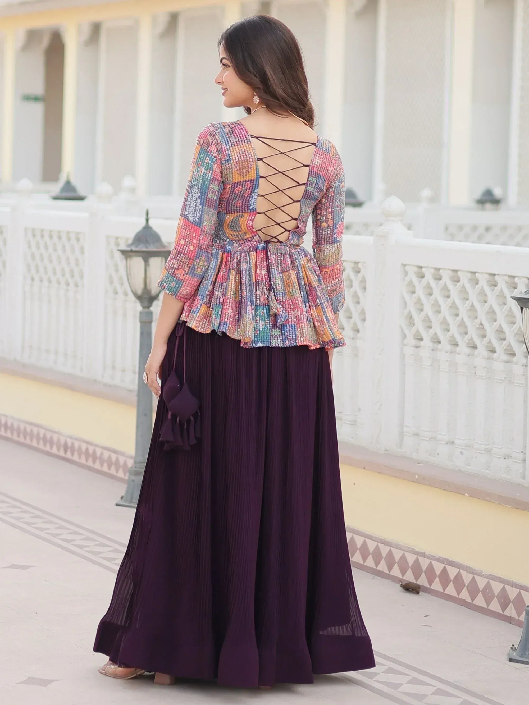 Woman in colorful sequin top with crisscross back and purple pleated skirt, ethnic wear outfit