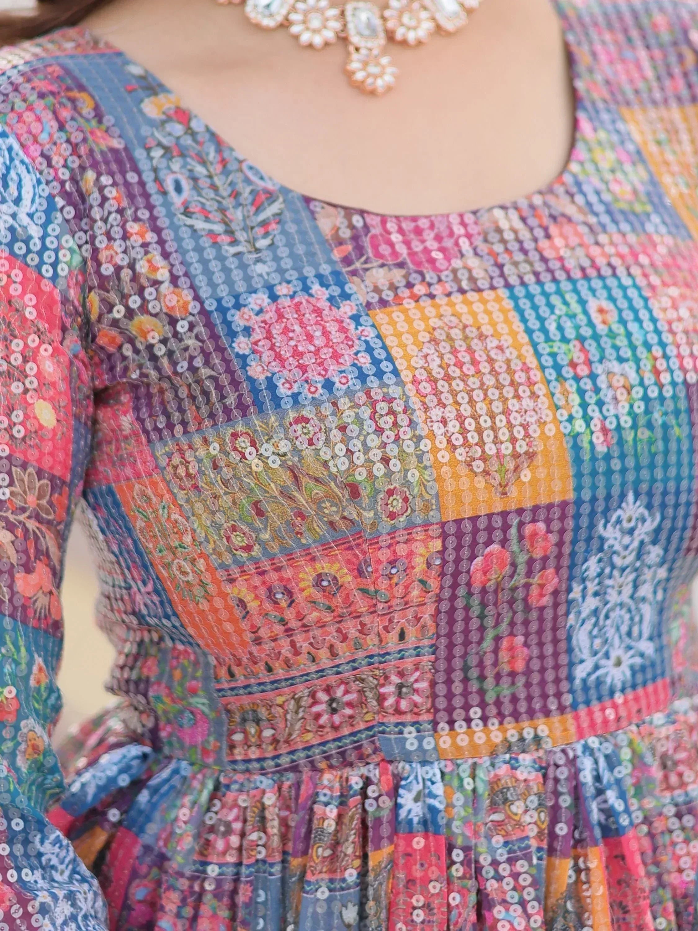 Colorful patchwork ethnic gown with sequins and floral prints, paired with statement necklace