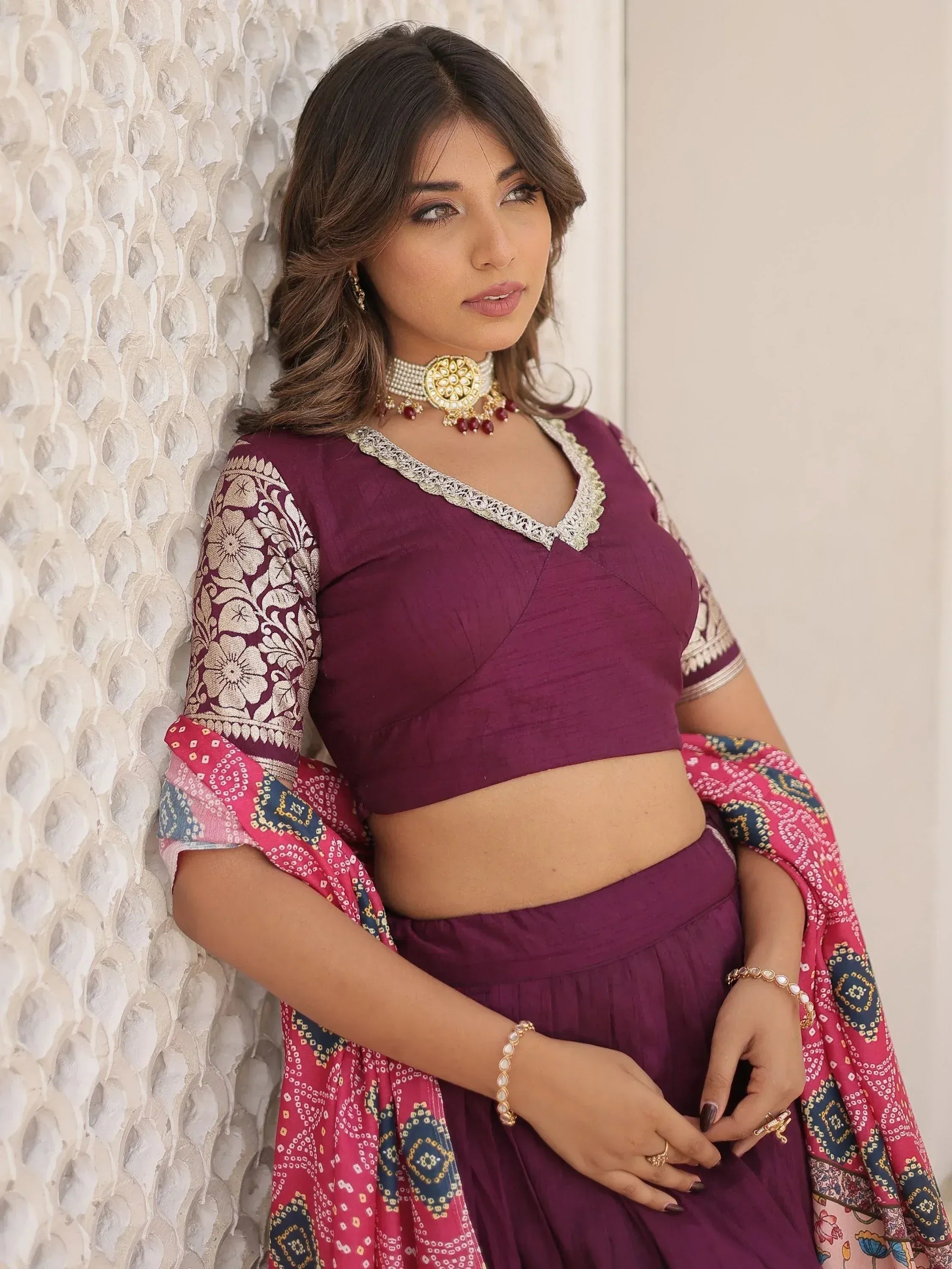 Woman in purple ethnic lehenga choli with floral sleeves and colorful dupatta, styled with traditional jewelry