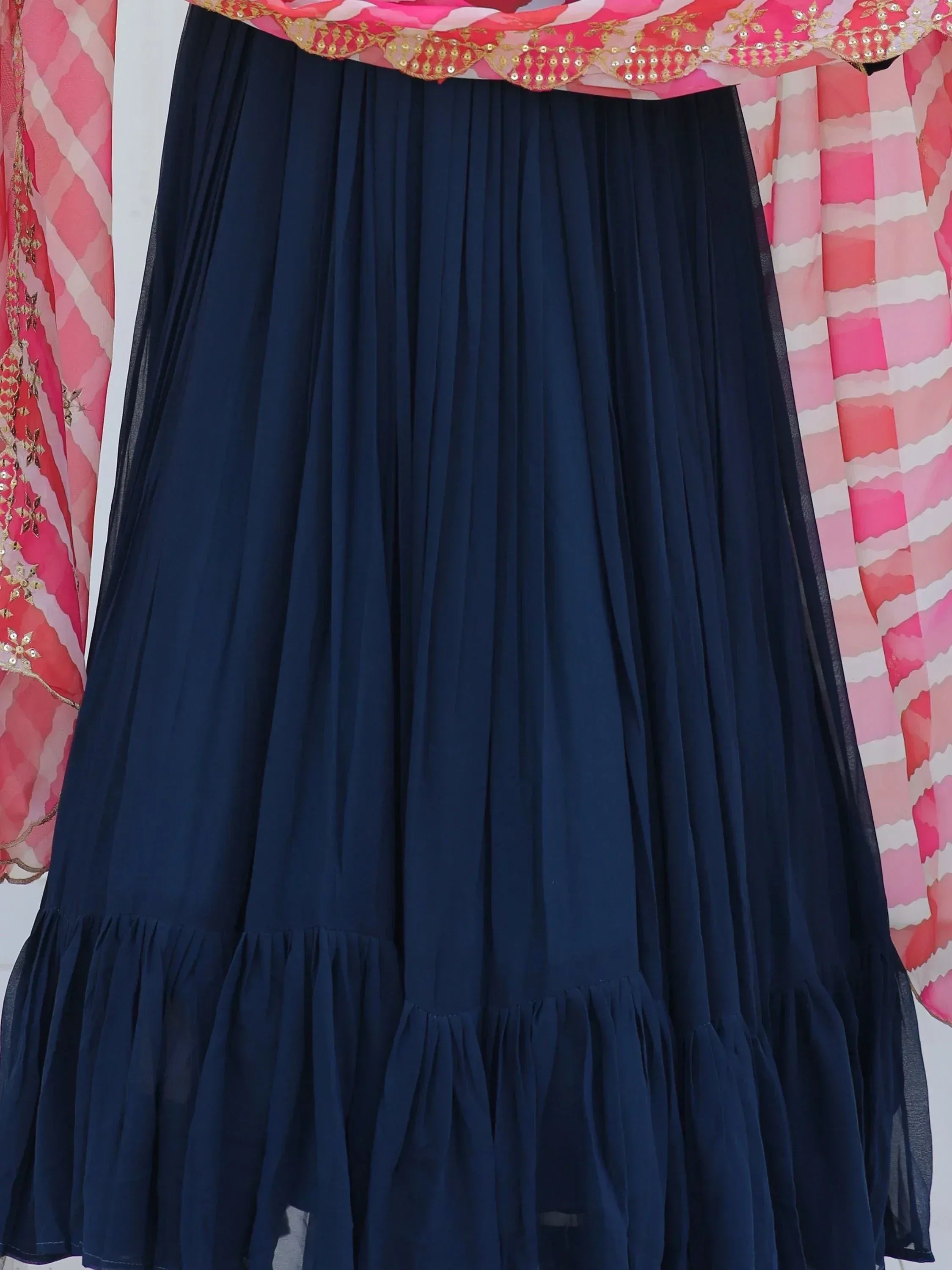 Navy blue pleated lehenga skirt with ruffled hem, paired with pink embroidered dupatta for ethnic wear