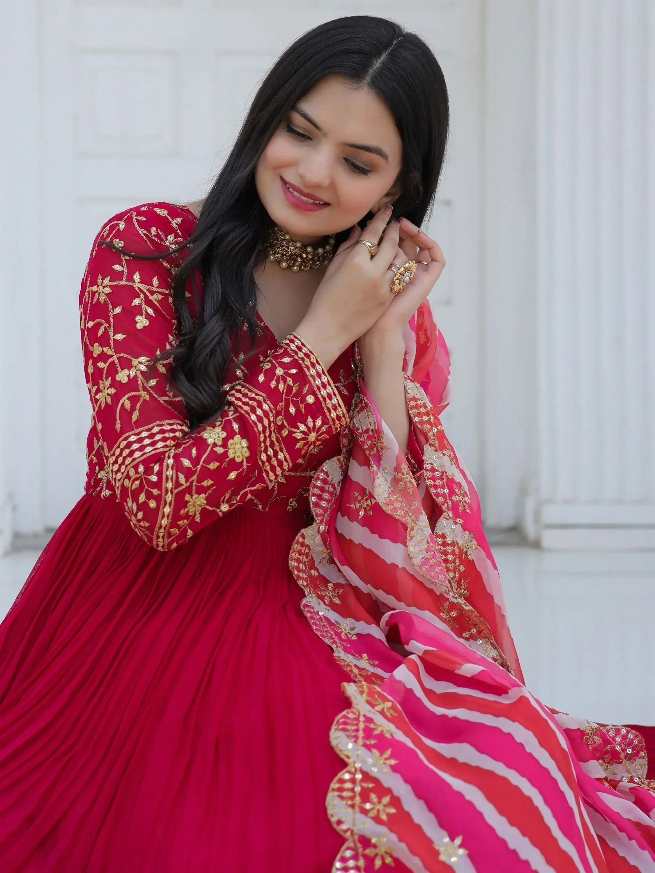 Red Indian ethnic gown with gold embroidery and pink dupatta, perfect for weddings and festivals