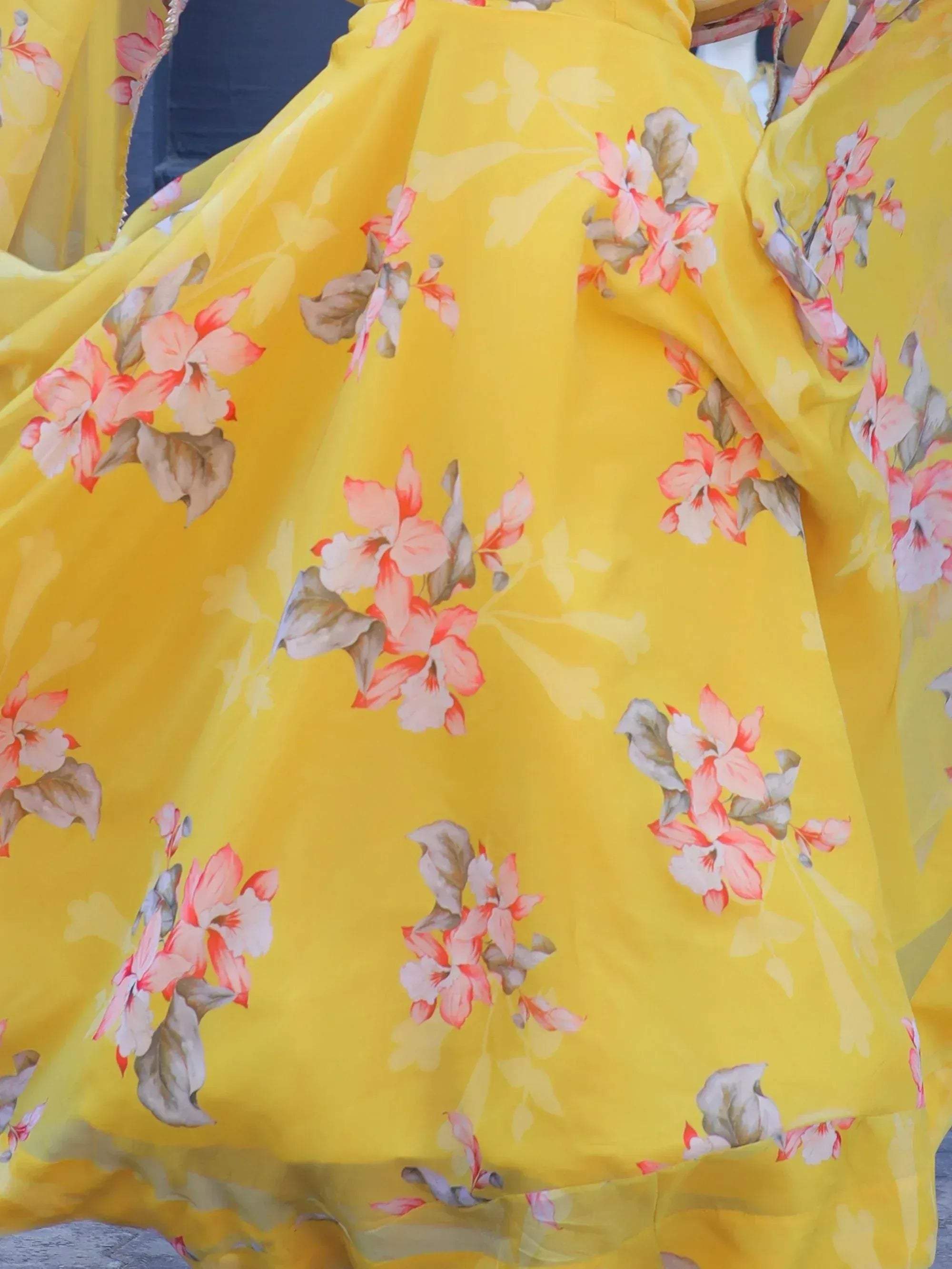 Yellow floral print ethnic gown with pink blossoms and green leaves, perfect for festive occasions.
