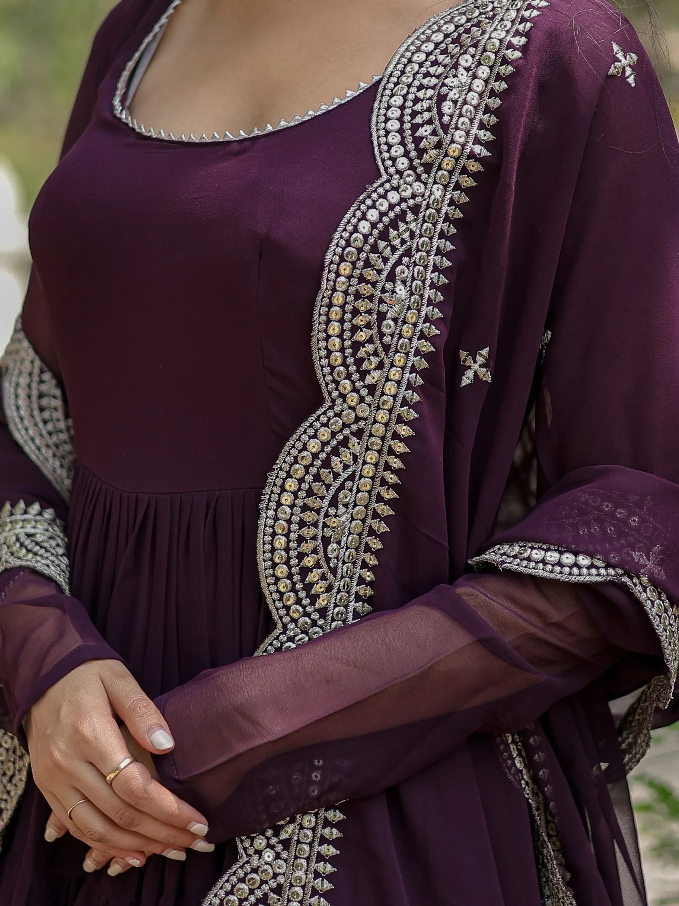 Woman wearing a purple embroidered Indian ethnic gown with detailed silver embellishments