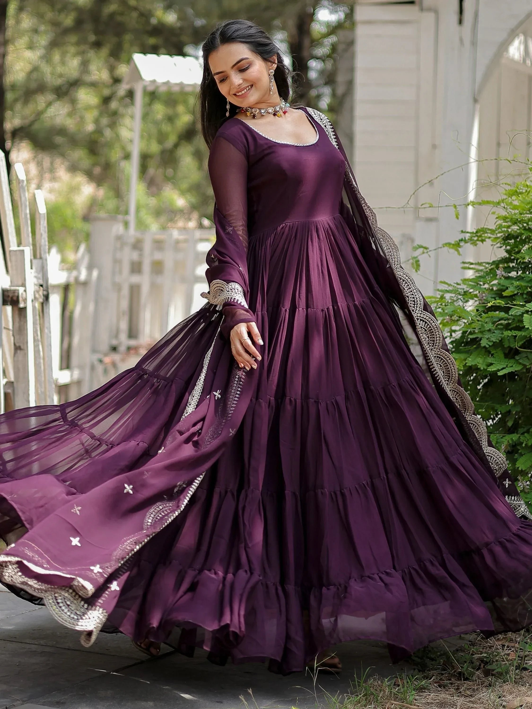 Woman in a purple ethnic gown with silver trim, outdoor garden setting, festive attire