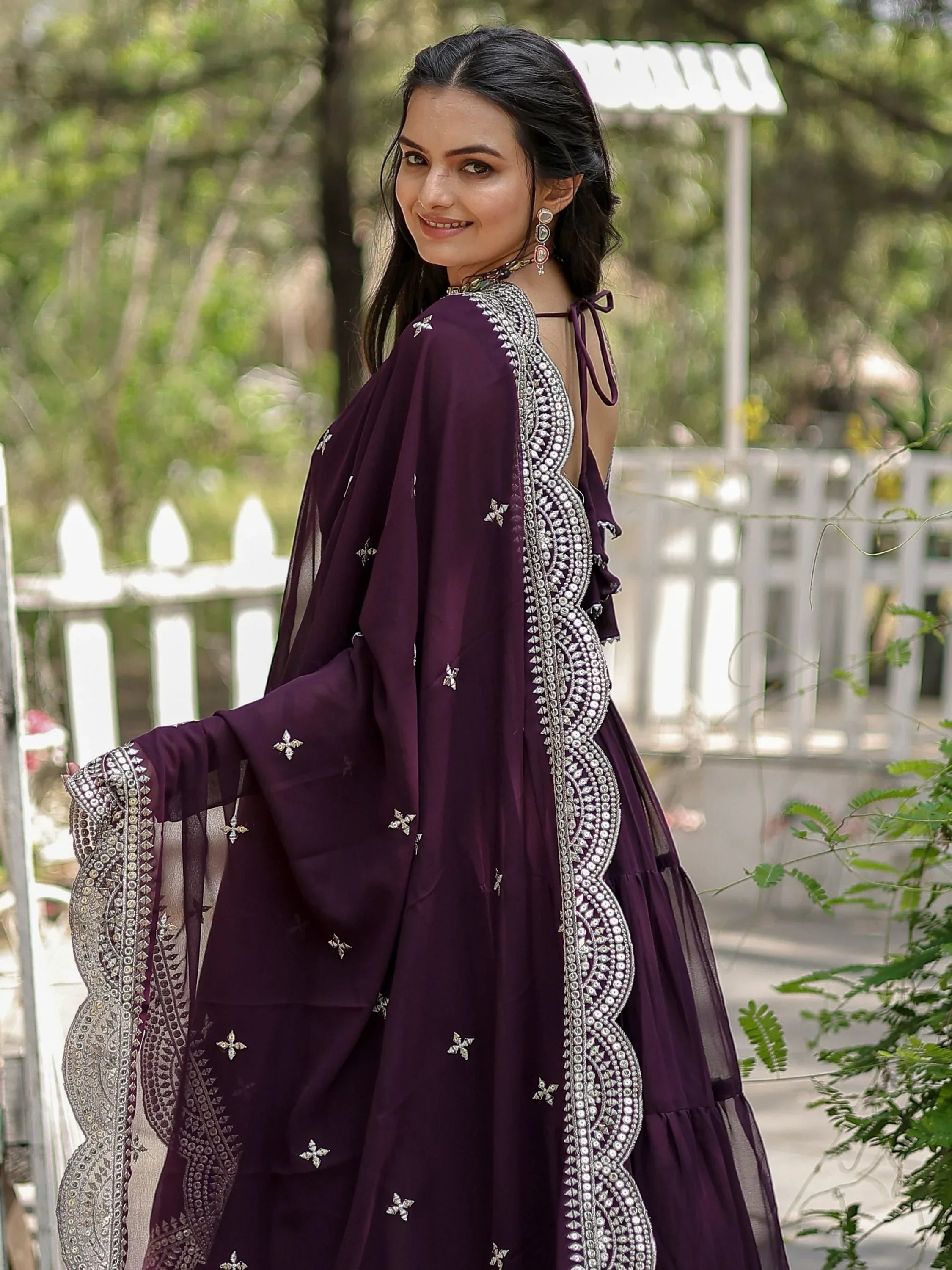 Woman in a purple embroidered lehenga choli with dupatta, outdoor setting