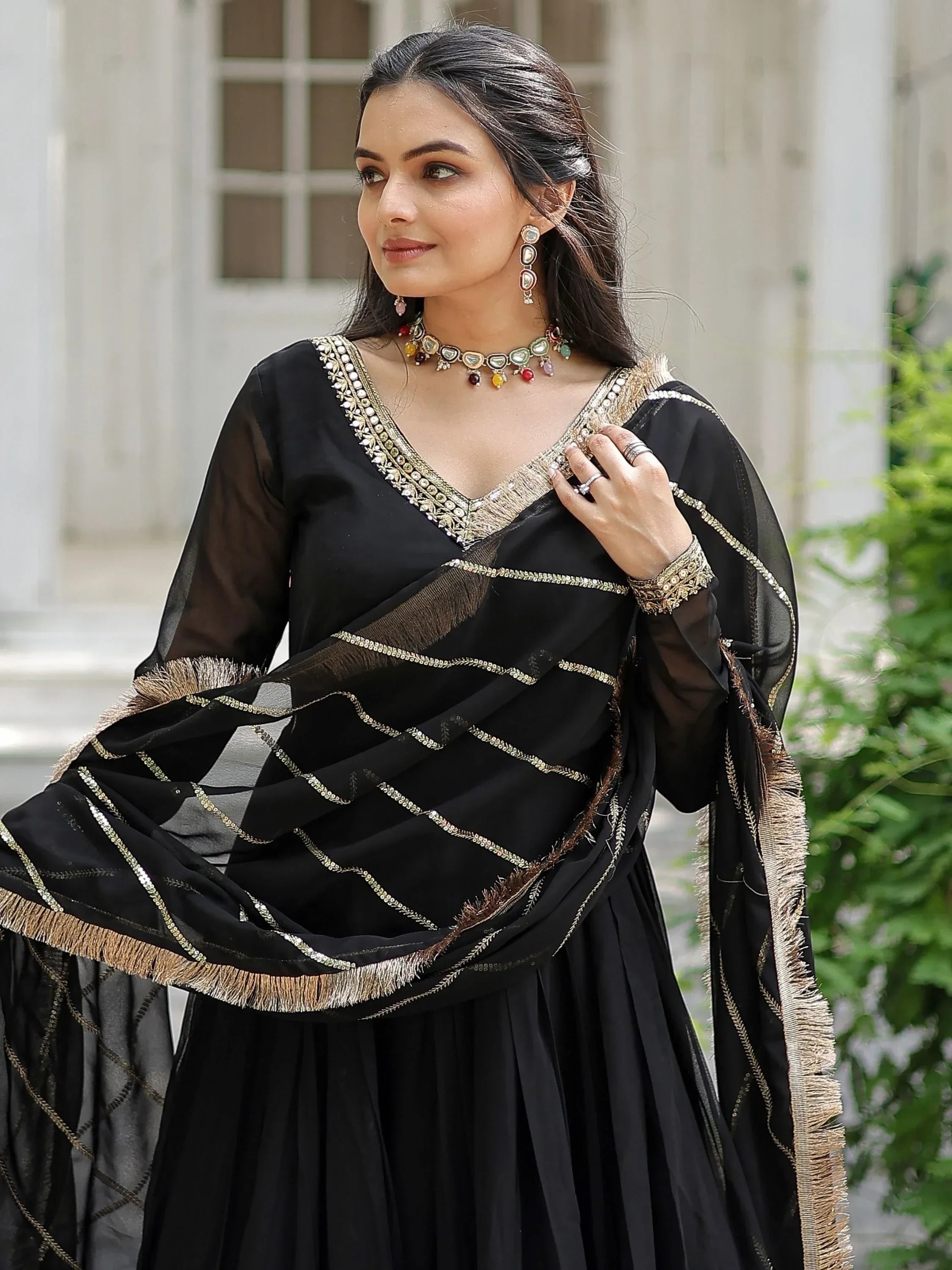 Woman wearing black ethnic anarkali suit with gold embroidery and matching dupatta