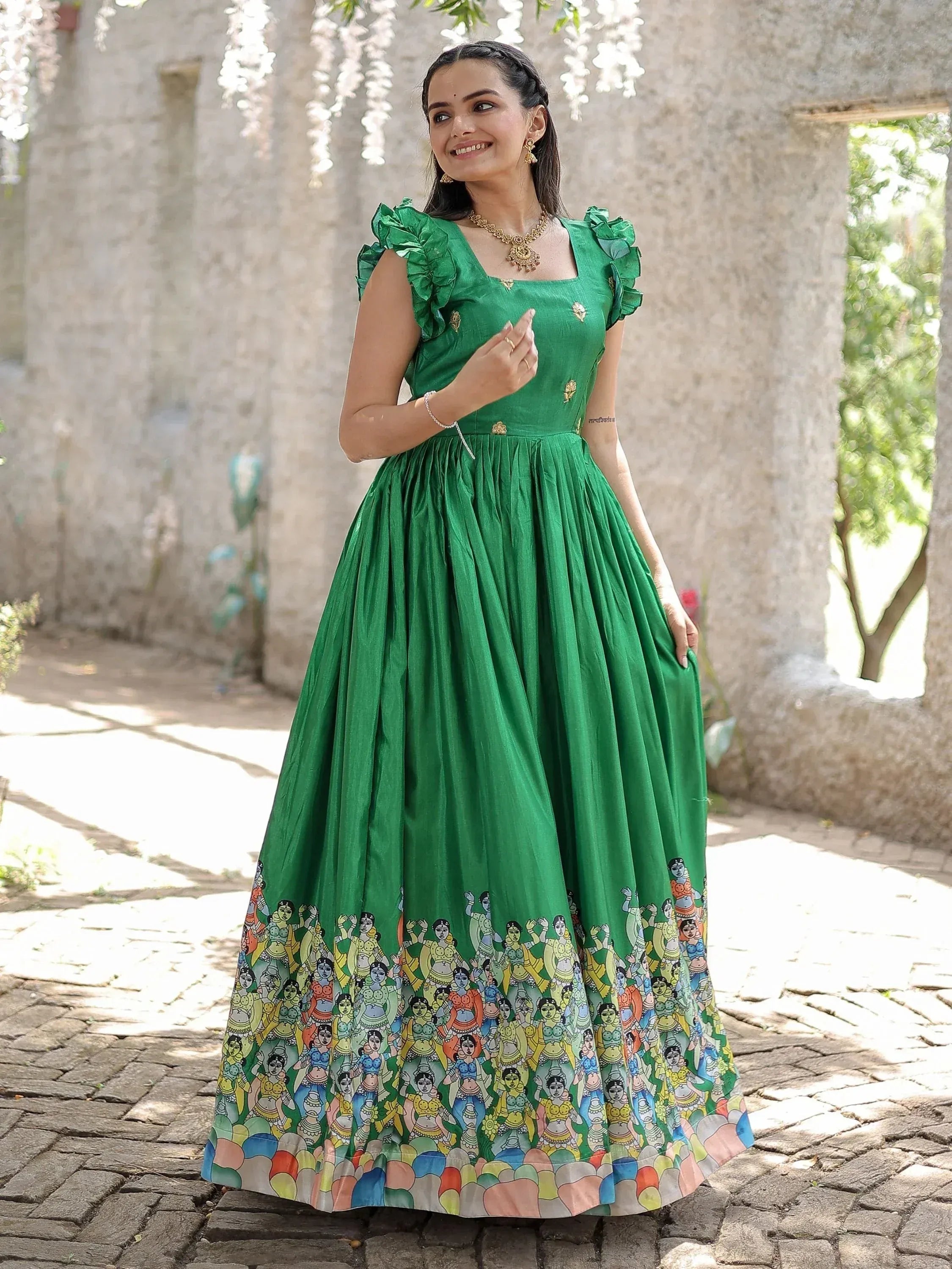 Green ethnic gown with ruffle sleeves and colorful folk art print, perfect for Indian occasions.