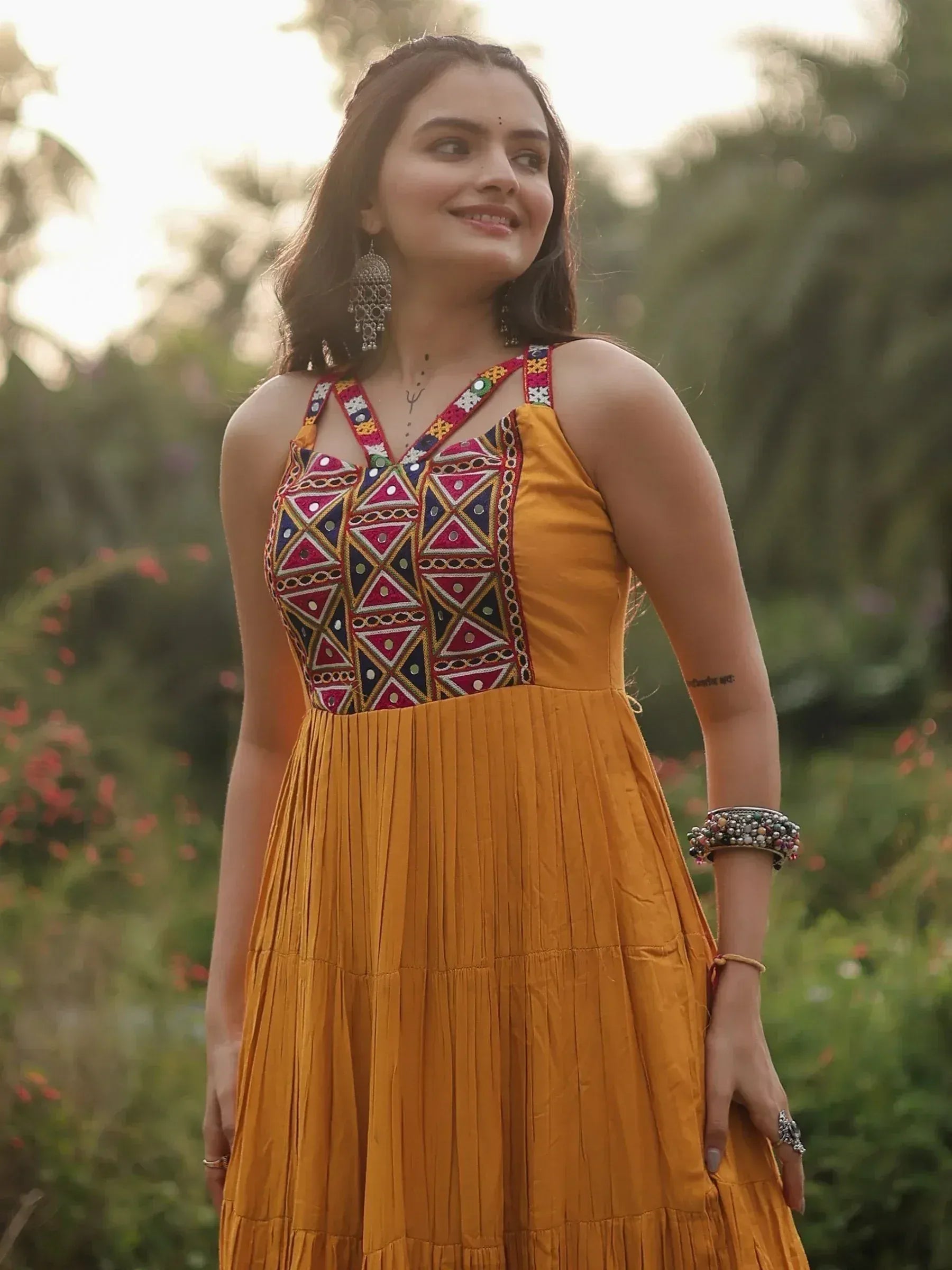 Mustard yellow ethnic gown with colorful mirror work and pleated skirt, perfect for Indian occasions