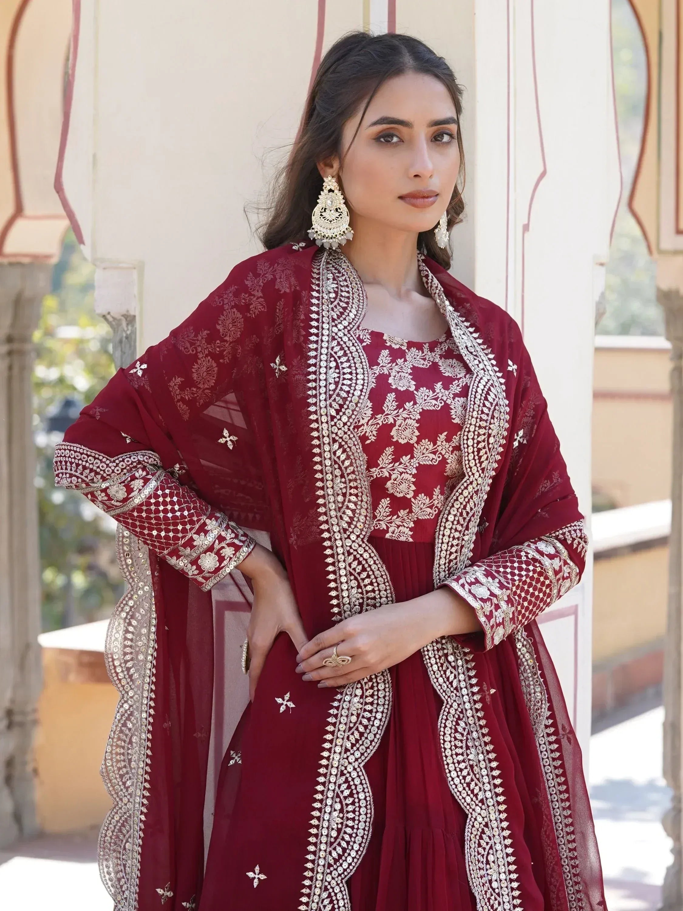 Woman in maroon embroidered ethnic gown with dupatta and statement earrings