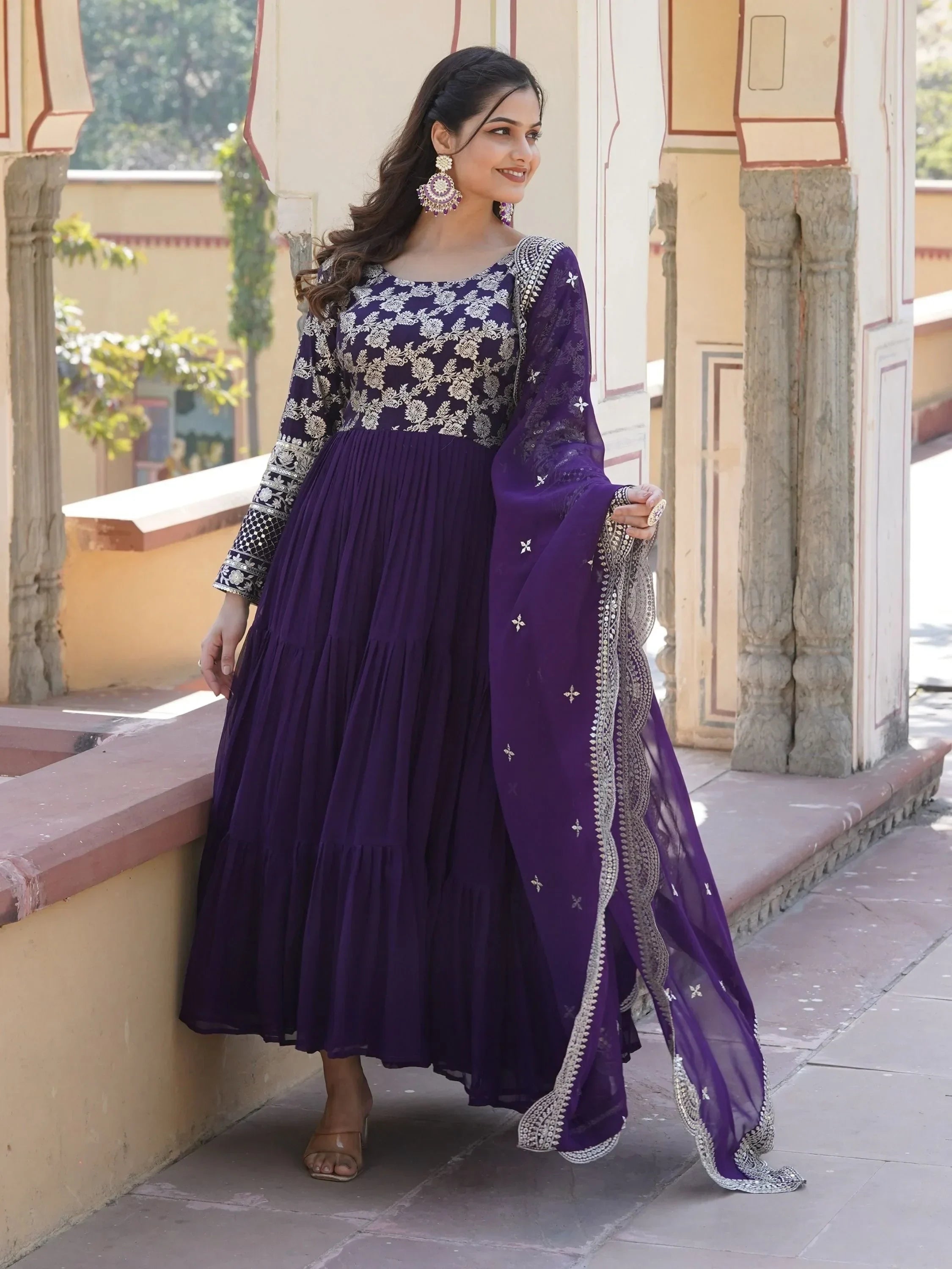 Woman in purple embroidered Anarkali gown with dupatta, elegant Indian ethnic wear outdoors