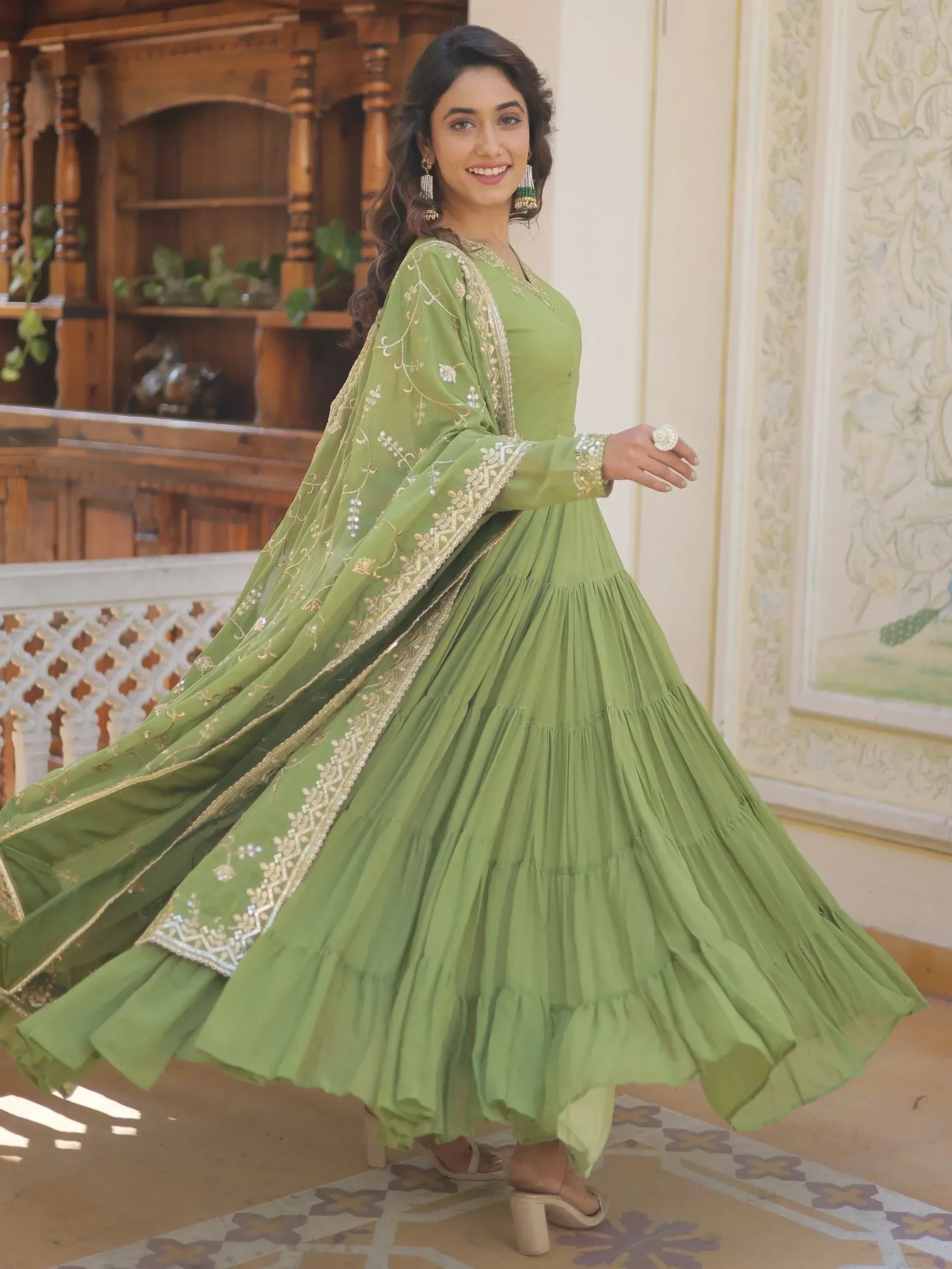 Green embroidered ethnic gown with layered skirt and gold detailing, perfect for festive occasions.