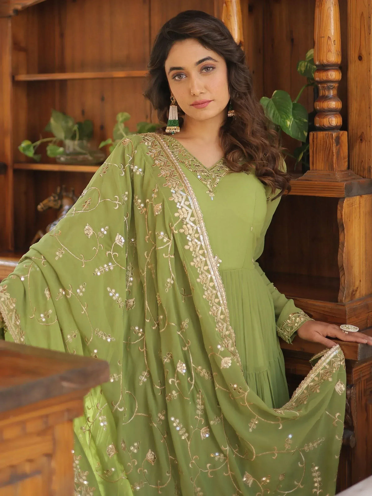 Green embroidered ethnic gown with gold threadwork and sequins, styled with traditional earrings