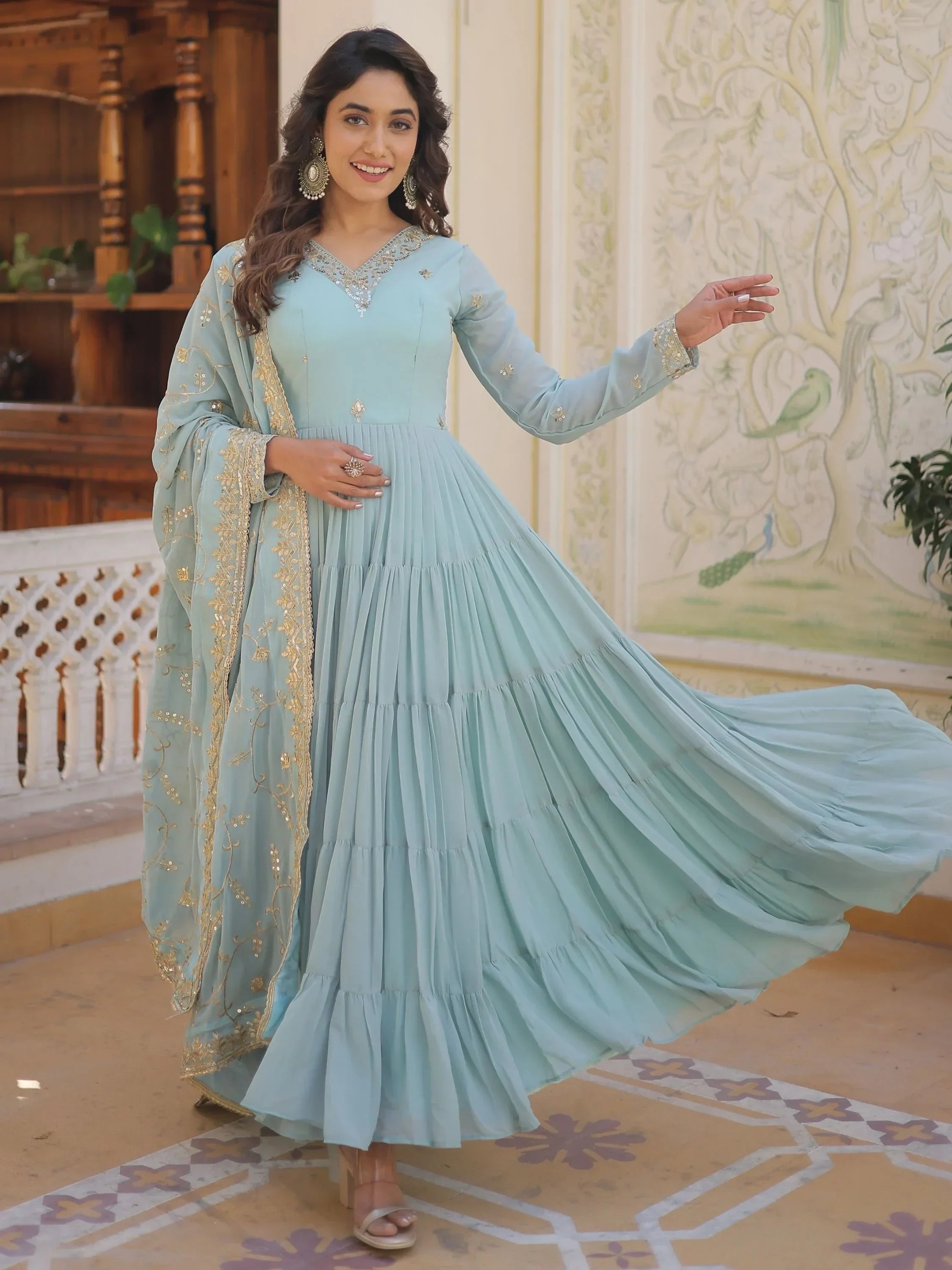 Woman in pastel blue embroidered Anarkali suit with dupatta, posing indoors