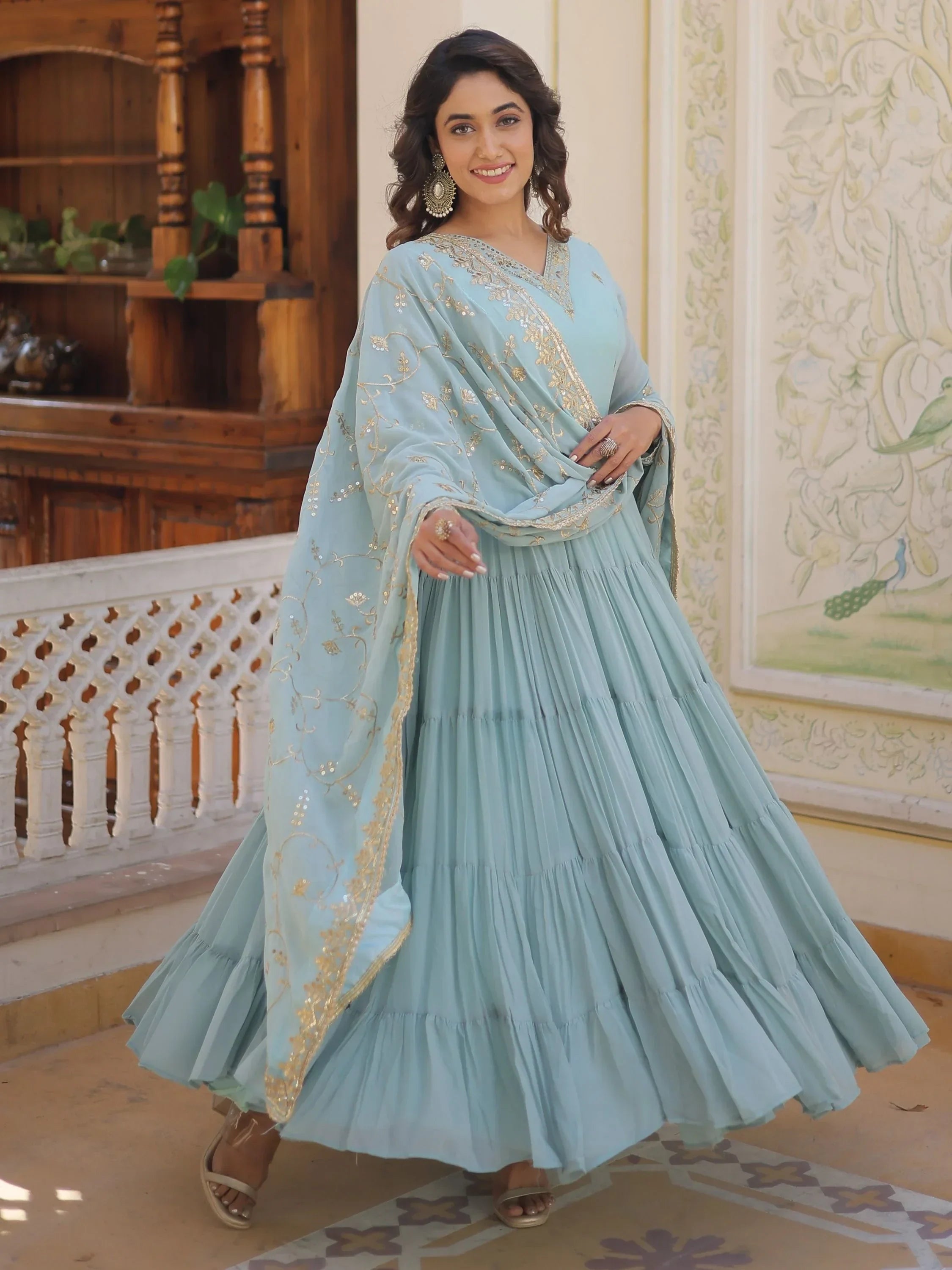 Woman in sky blue embroidered ethnic gown with dupatta, smiling indoors