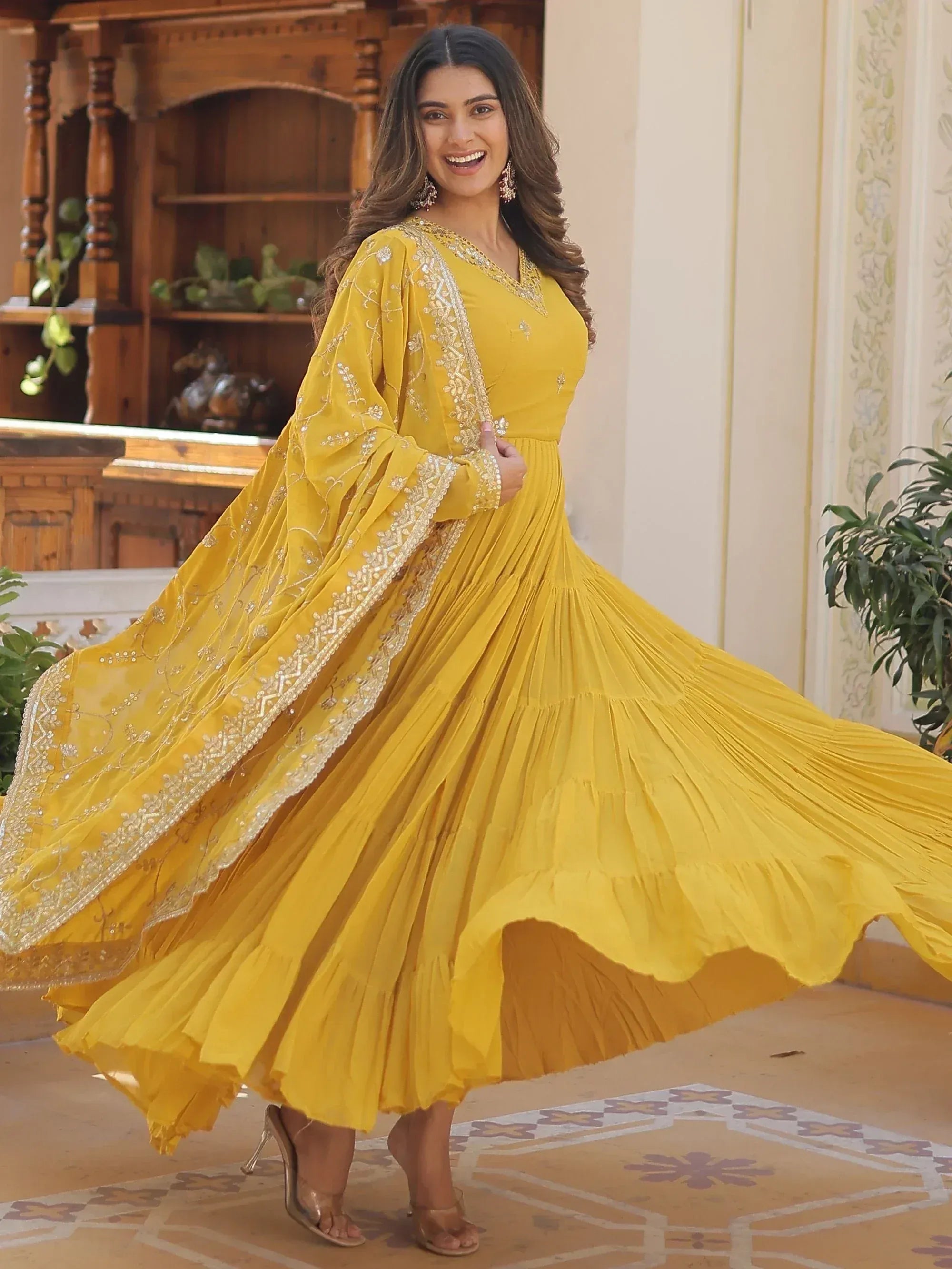 Yellow ethnic gown with gold embroidery, pleated skirt, and flared sleeves for festive occasions