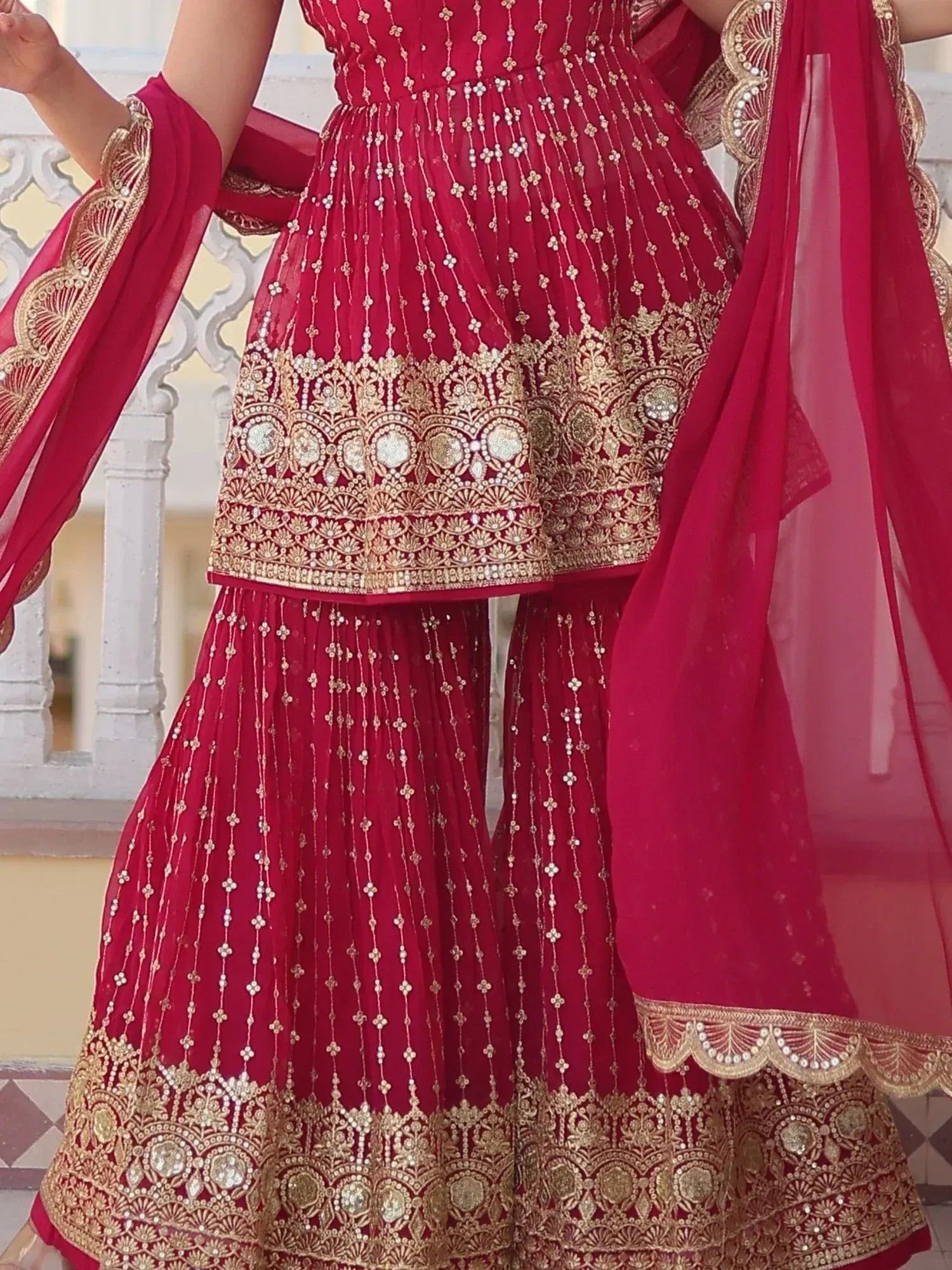 Red ethnic sharara suit with gold embroidery and matching dupatta, perfect for Indian weddings and festive occasions.