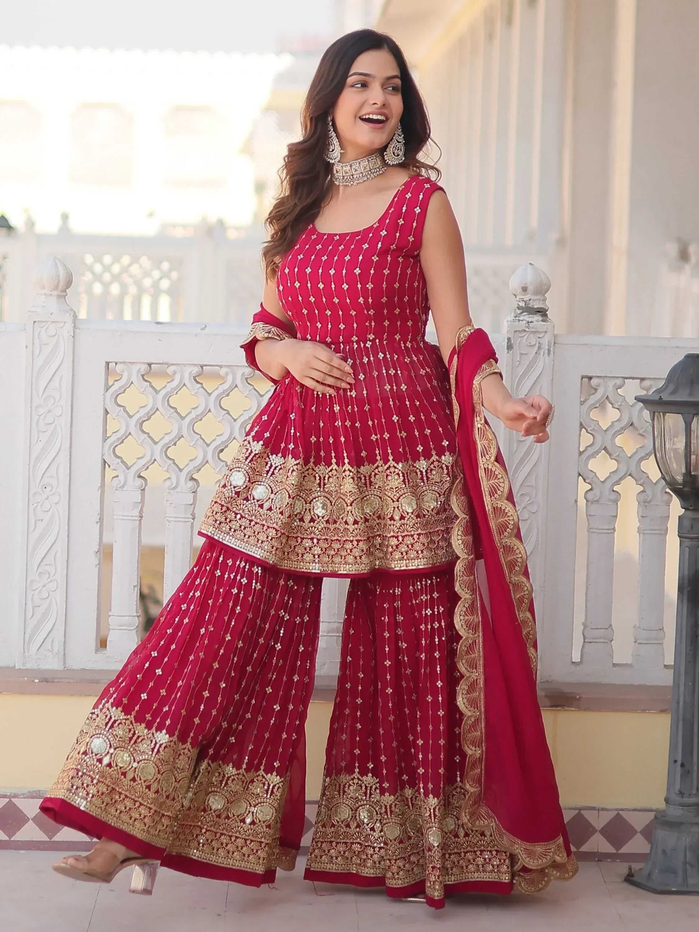 Red and gold embroidered Indian sharara suit with dupatta, perfect for weddings and festive occasions.