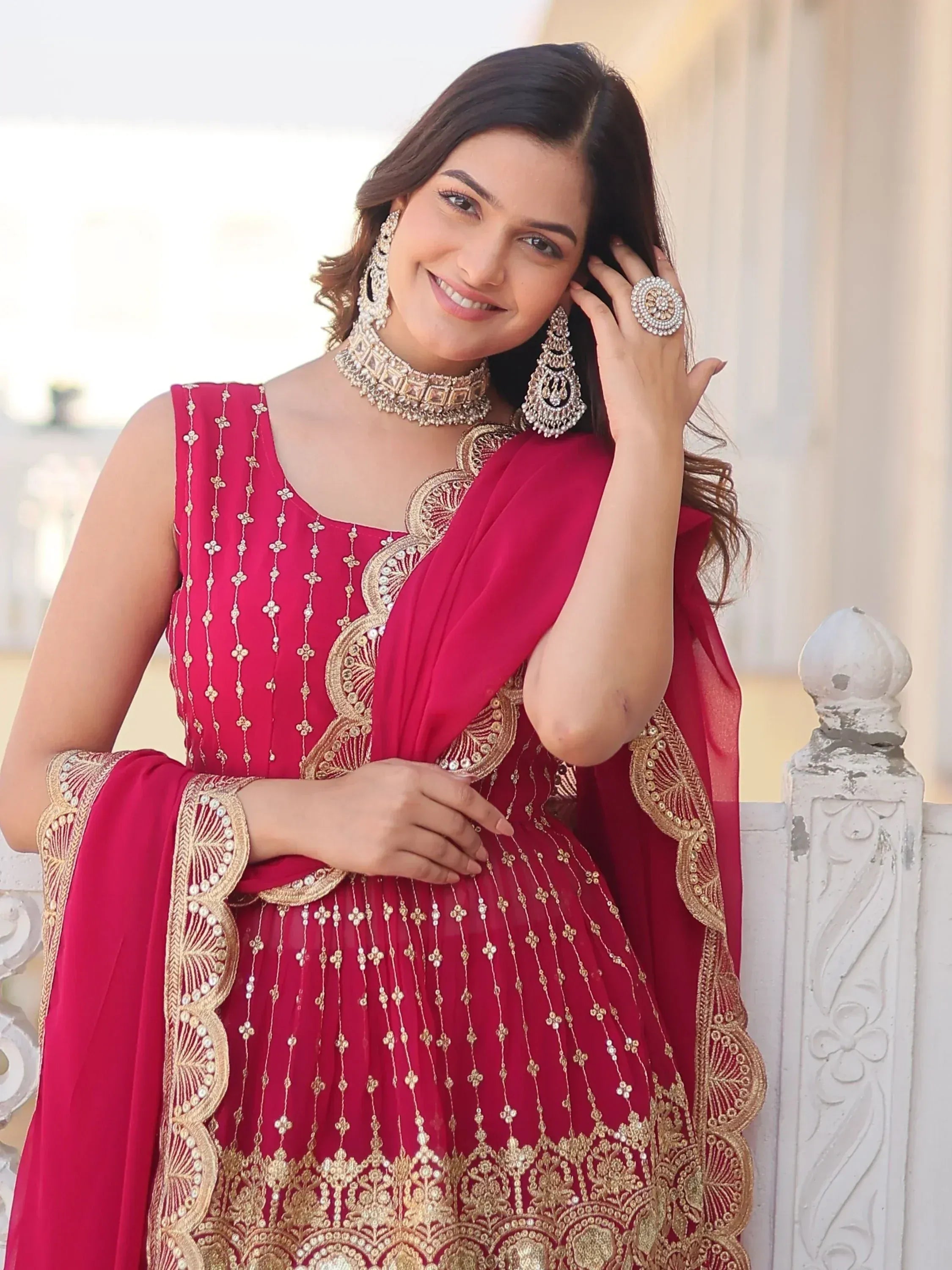 Woman in red ethnic gown with gold embroidery, perfect for Indian weddings or festive occasions.