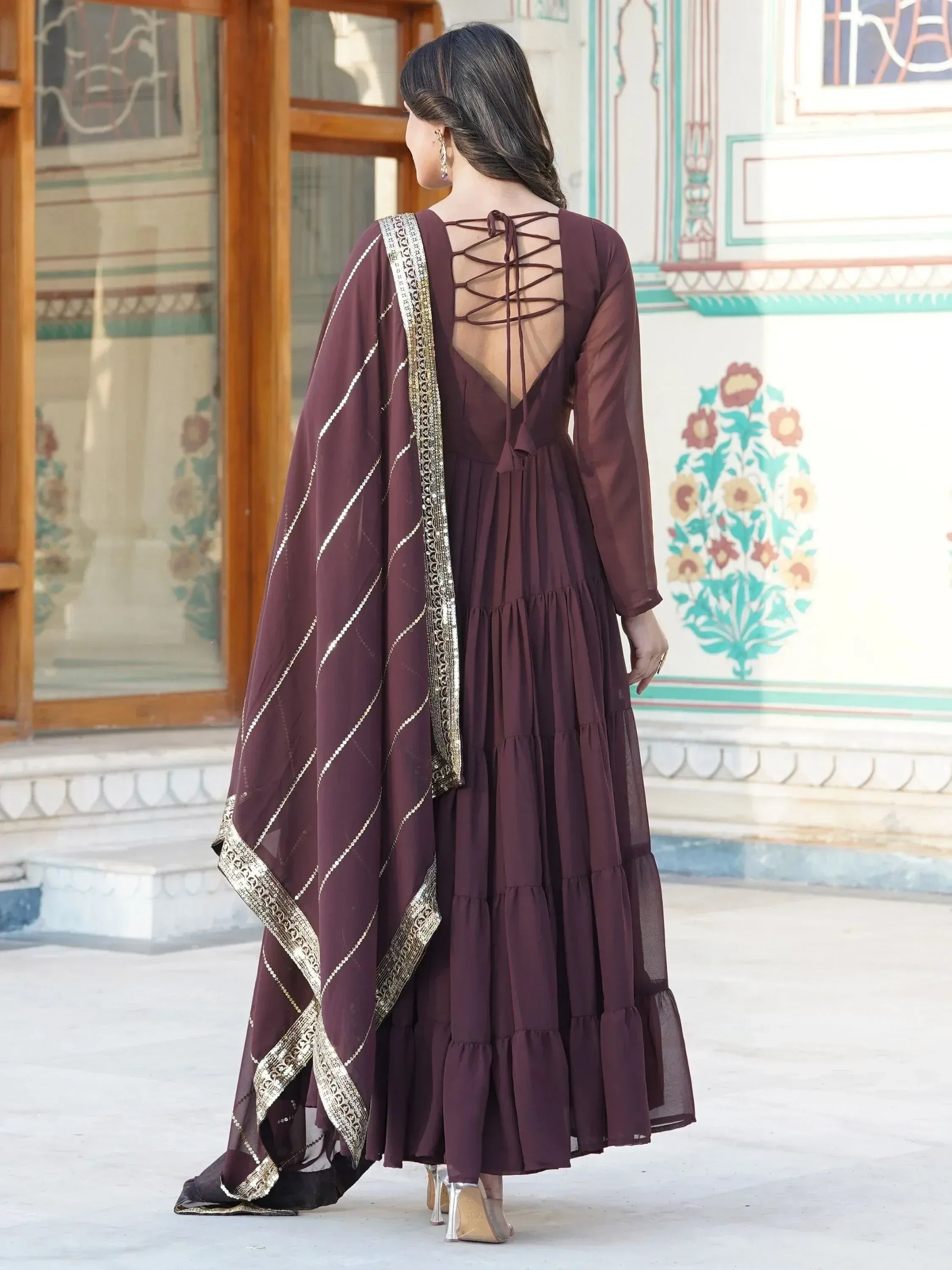 Woman wearing brown ethnic gown with gold-trimmed dupatta and criss-cross back design