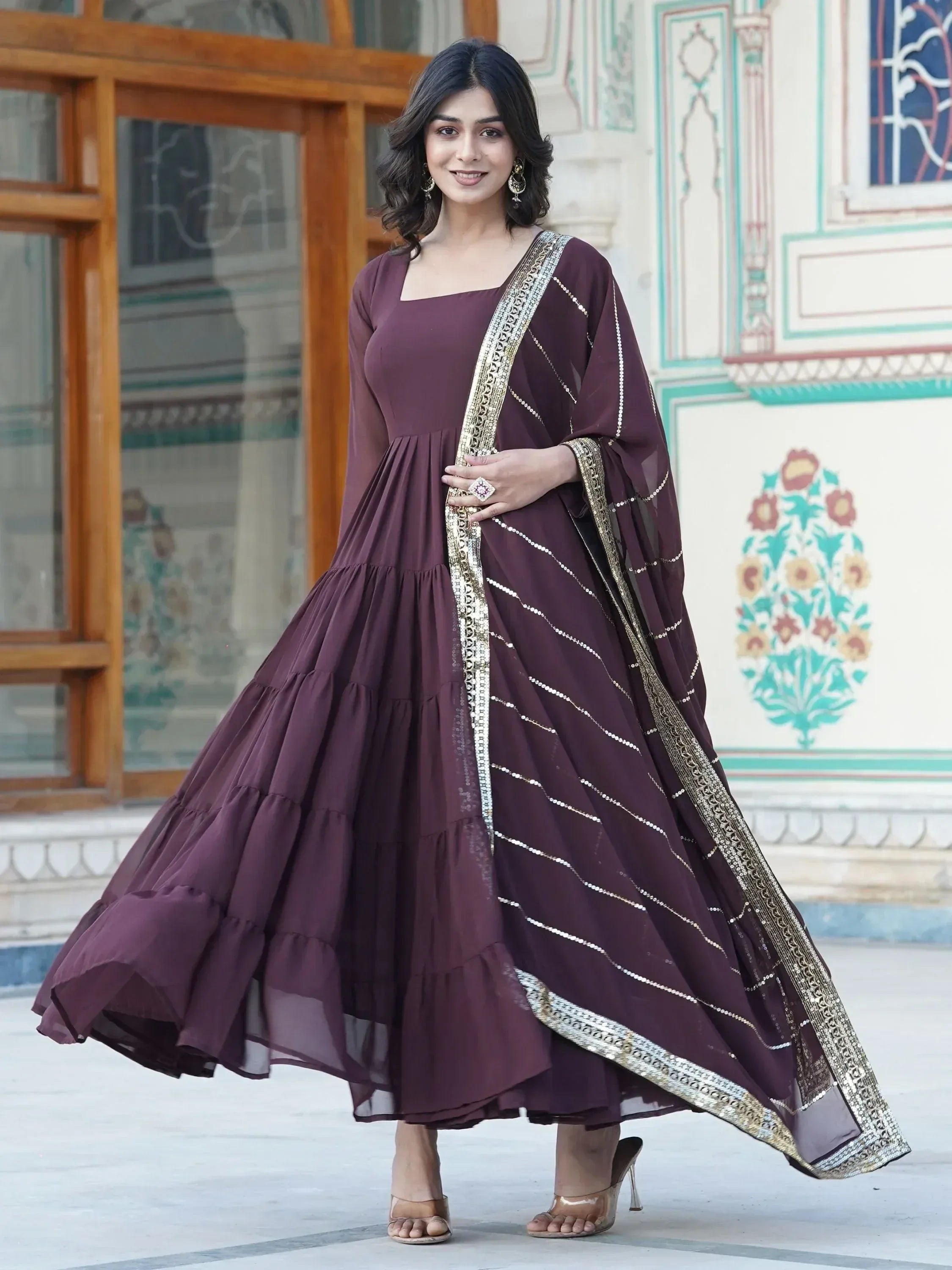 Woman wearing a brown tiered ethnic gown with gold-trim dupatta, stylish ethnic outfit