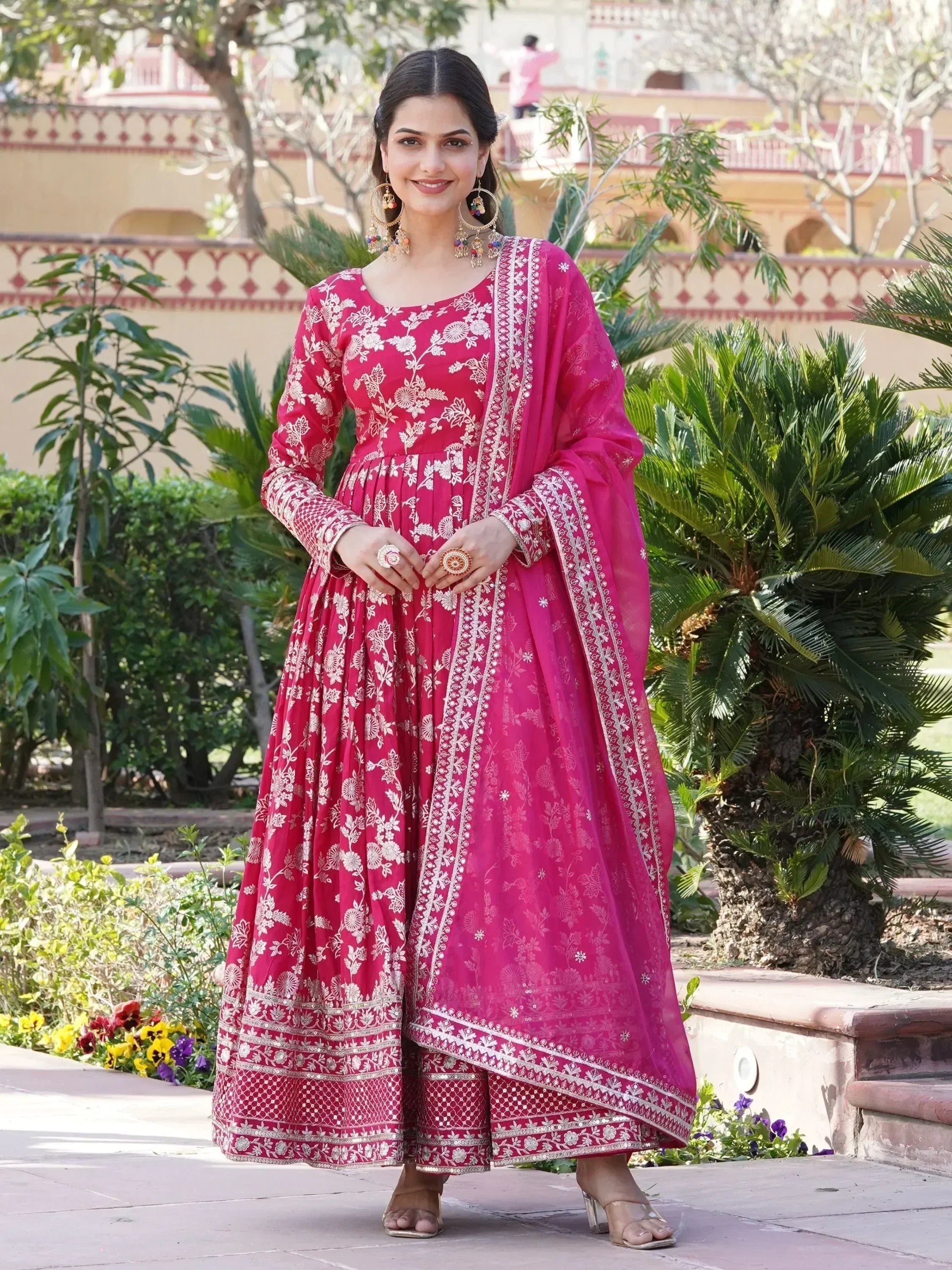 Woman in pink embroidered ethnic gown with dupatta, traditional Indian attire outdoors