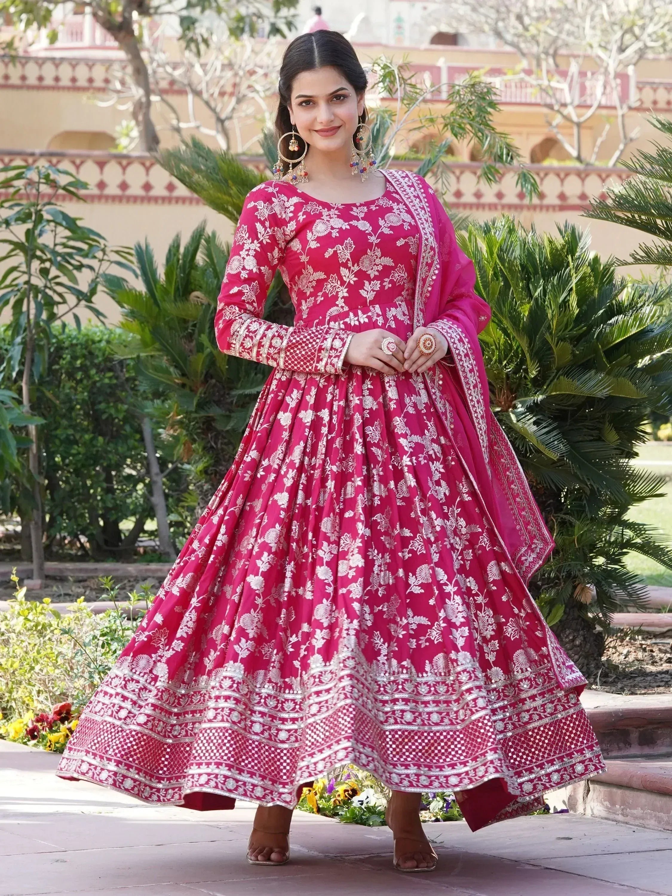 Woman in pink floral embroidered Anarkali dress with dupatta, outdoor garden setting