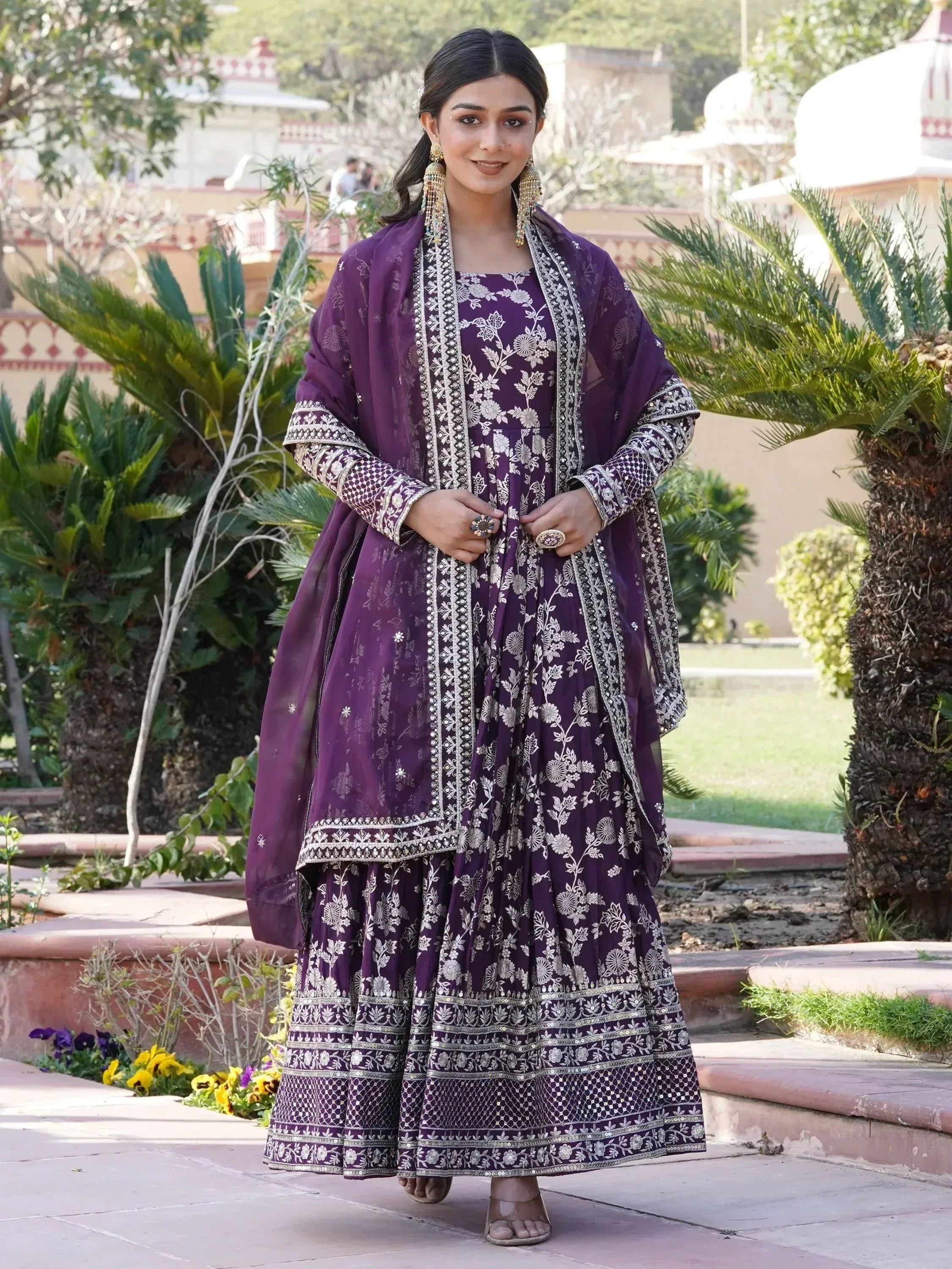 Woman wearing a purple embroidered ethnic gown with dupatta, outdoor garden setting