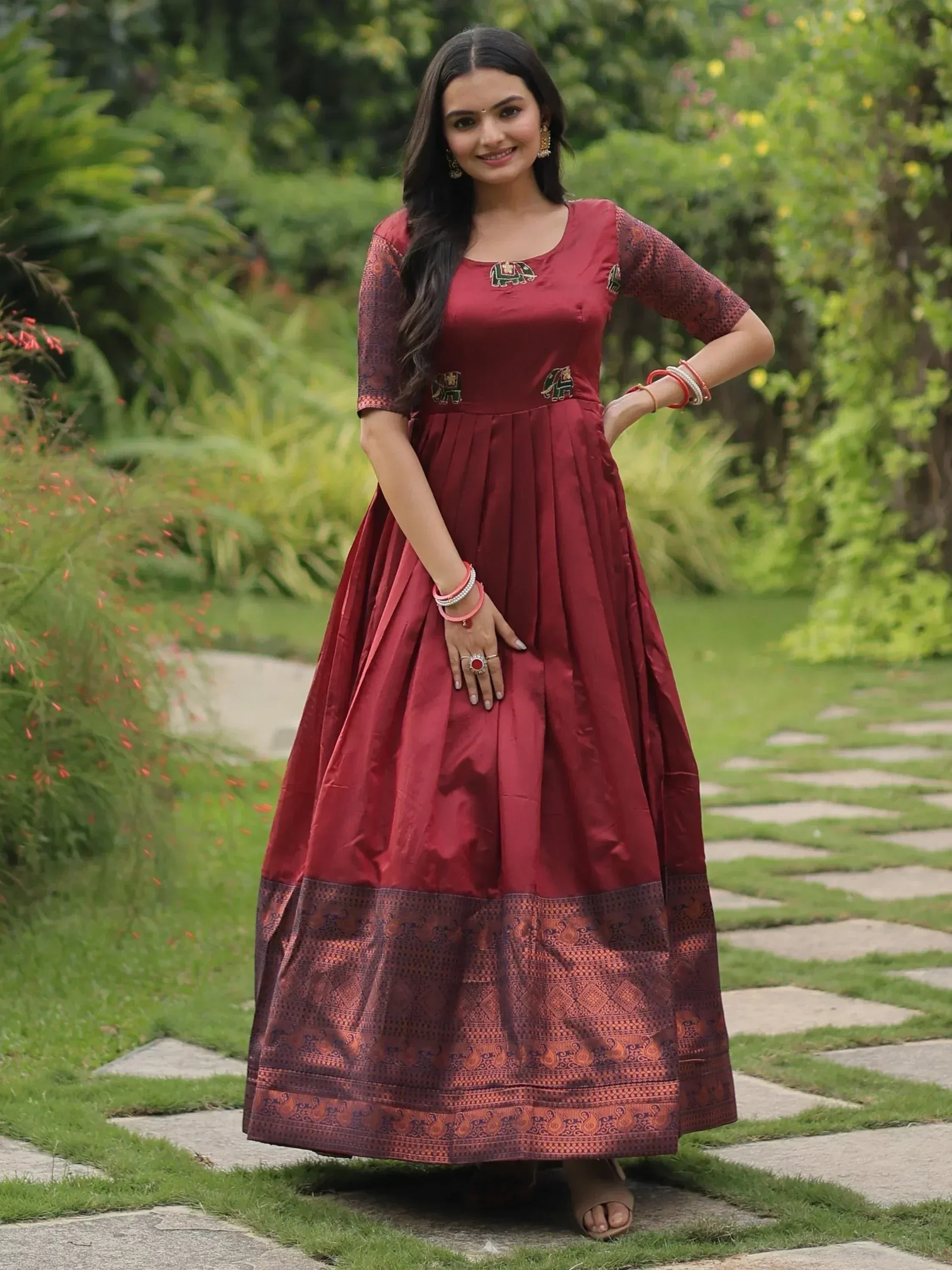 Maroon ethnic gown with elephant embroidery and patterned hem, perfect for Indian occasions