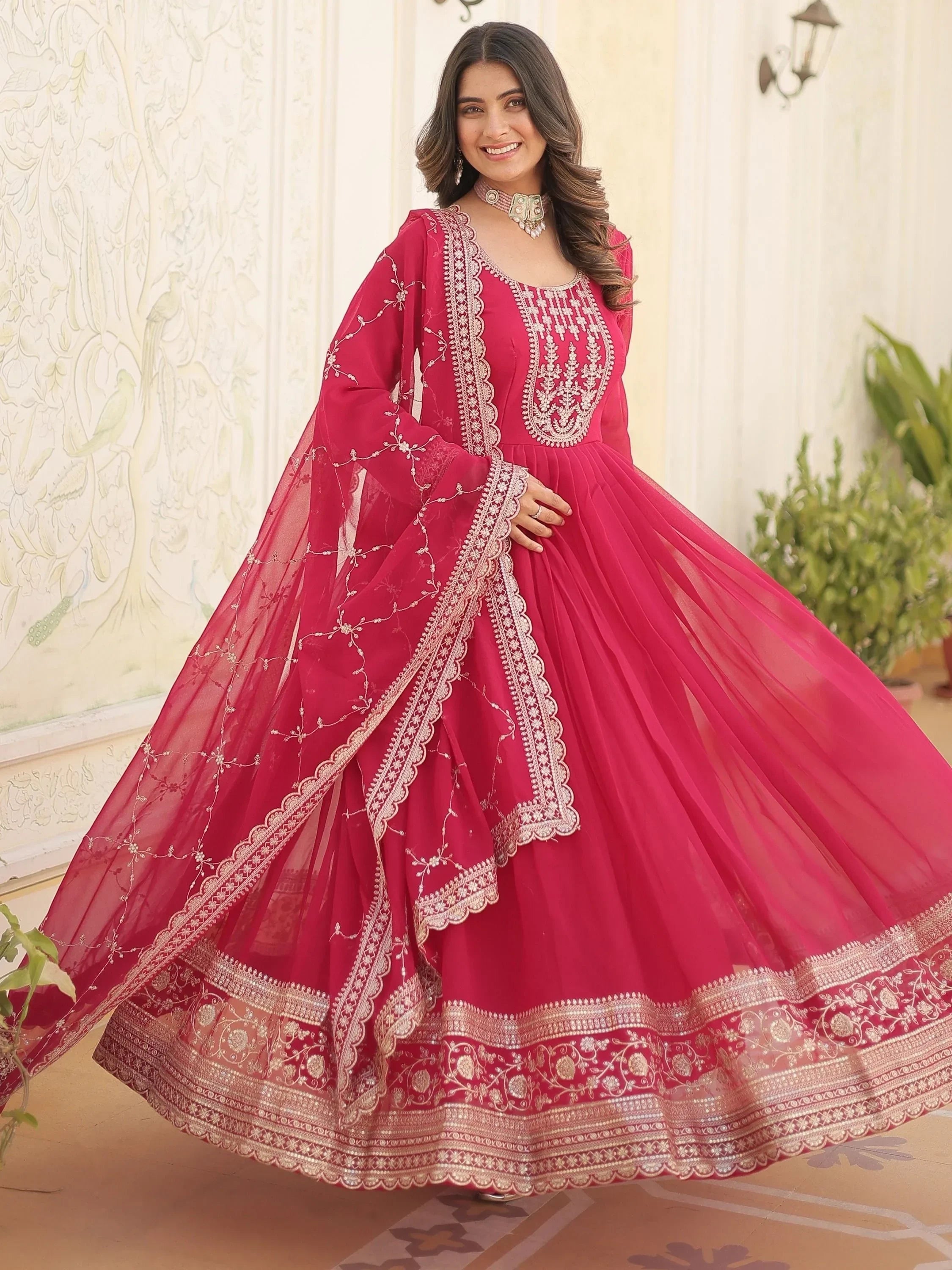 Woman in bright pink embroidered lehenga choli with net dupatta, traditional Indian attire